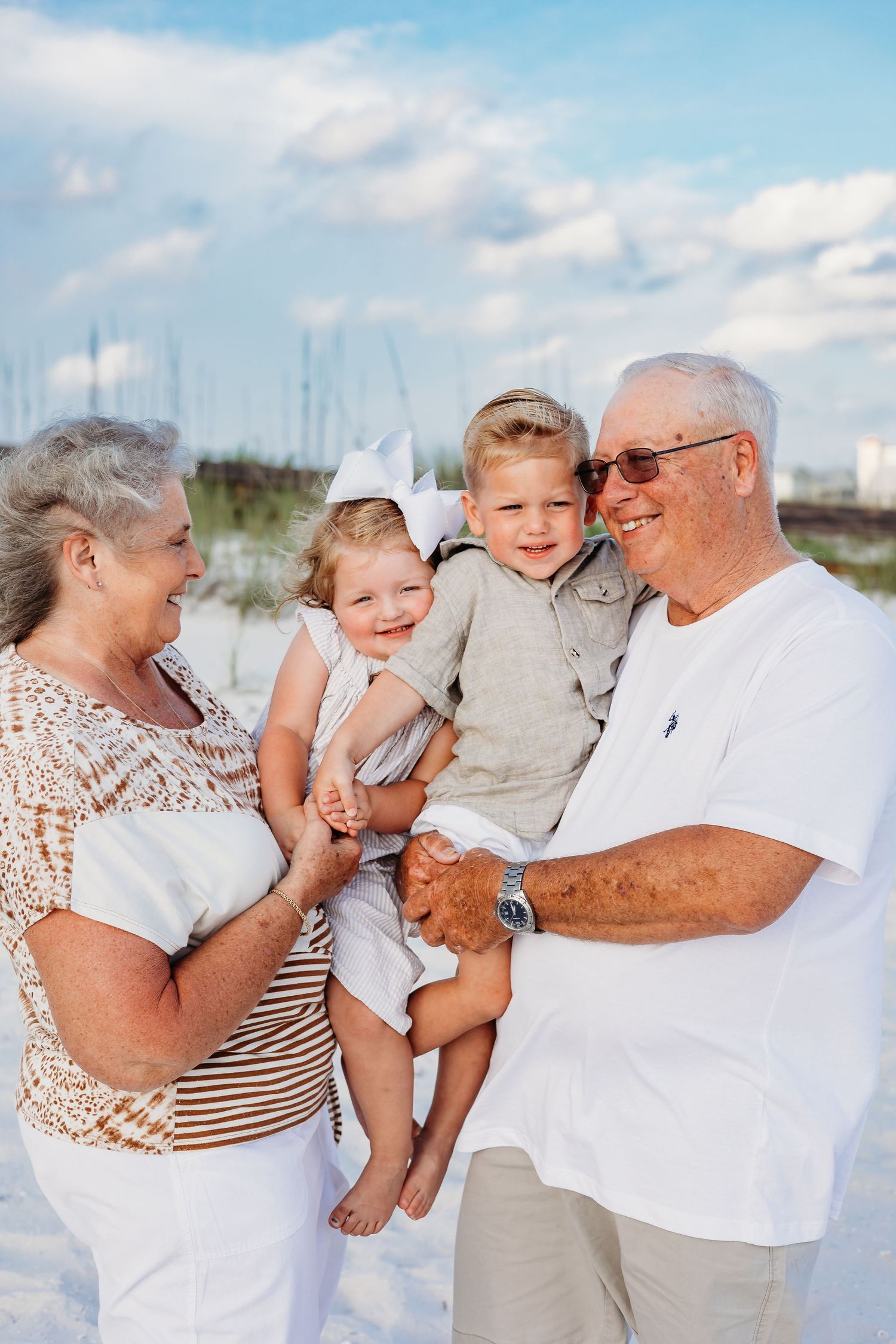 Multi-generational family enjoying a fun photoshoot on white sandy beach.