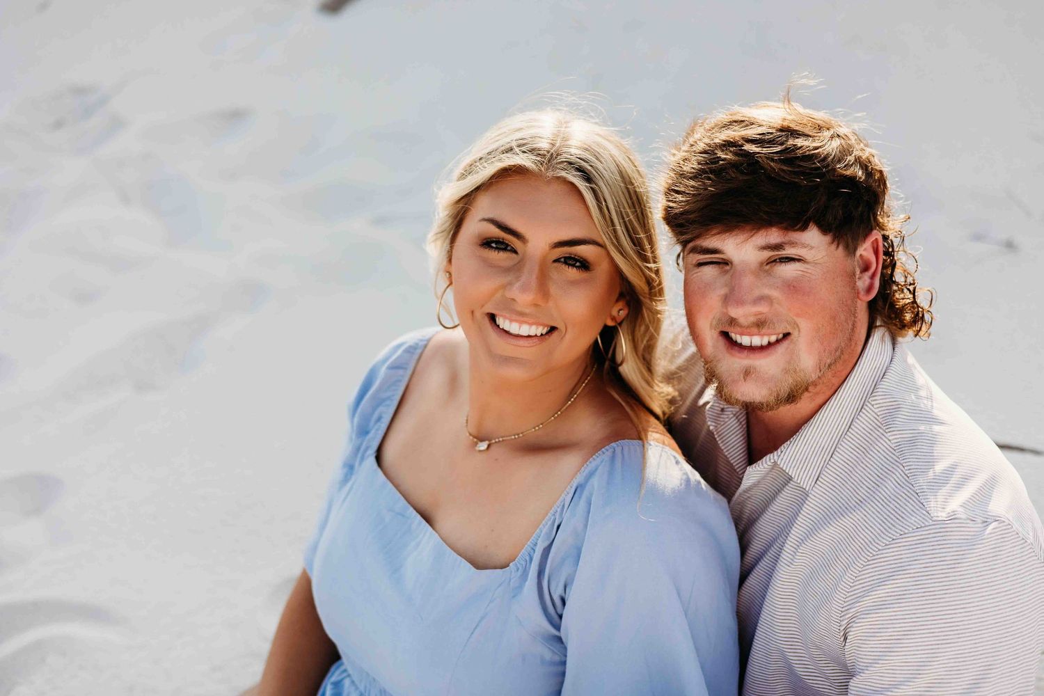 Happy couple laughing together during casual beach photo session.