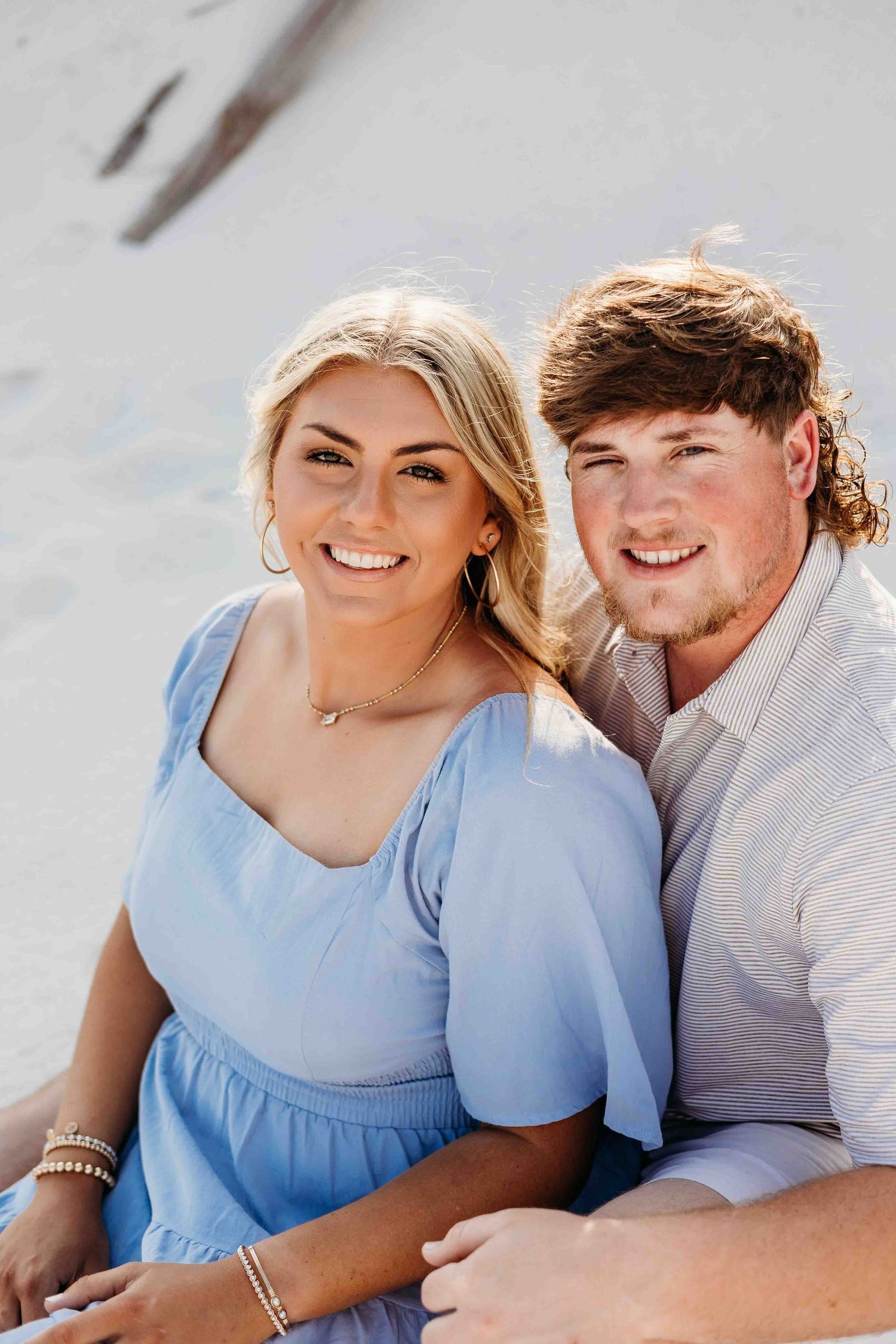 Couple sharing joyful moments during beach engagement photography session.