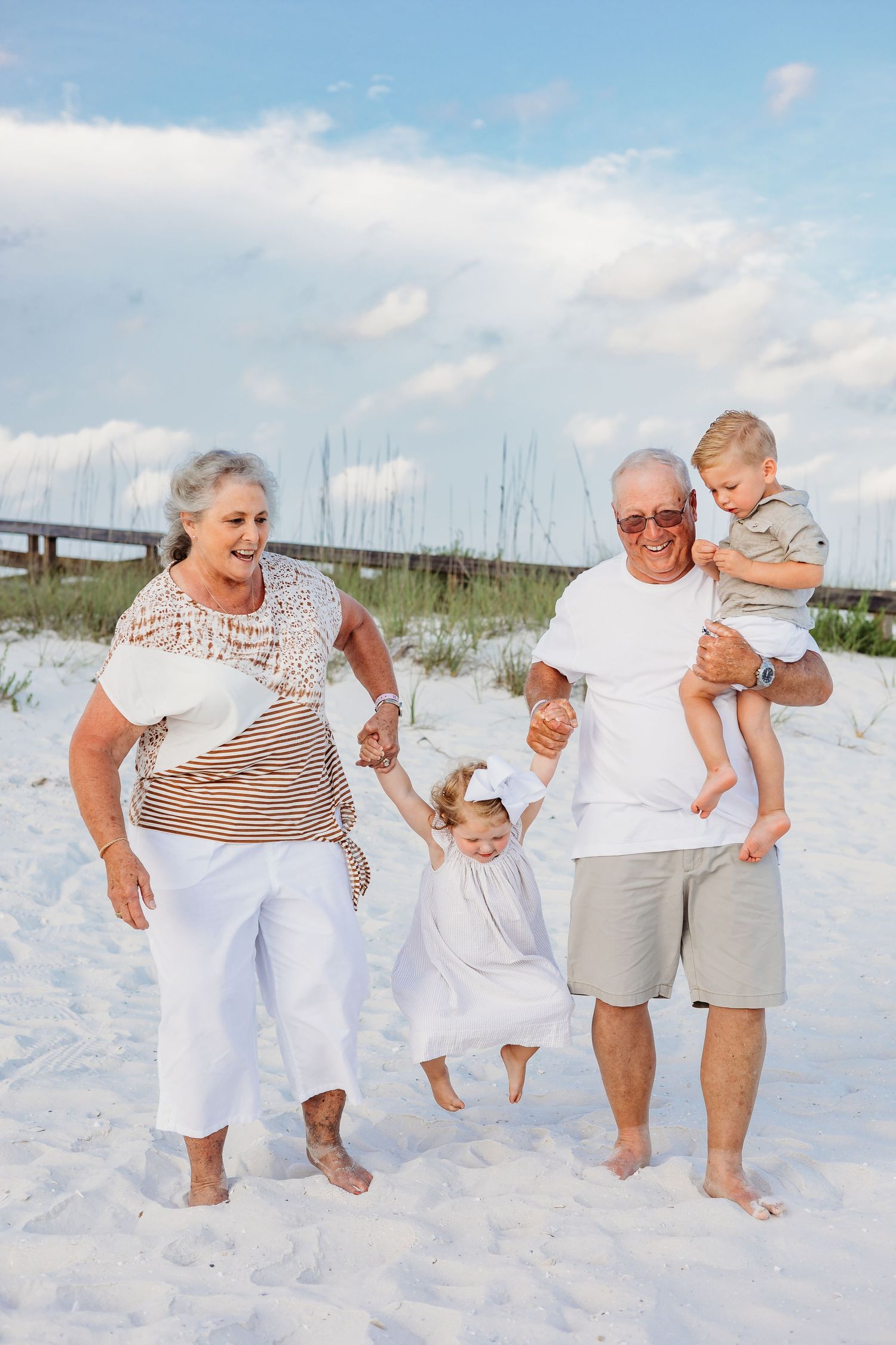 Playful family beach portraits showing movement and laughter on white sand.