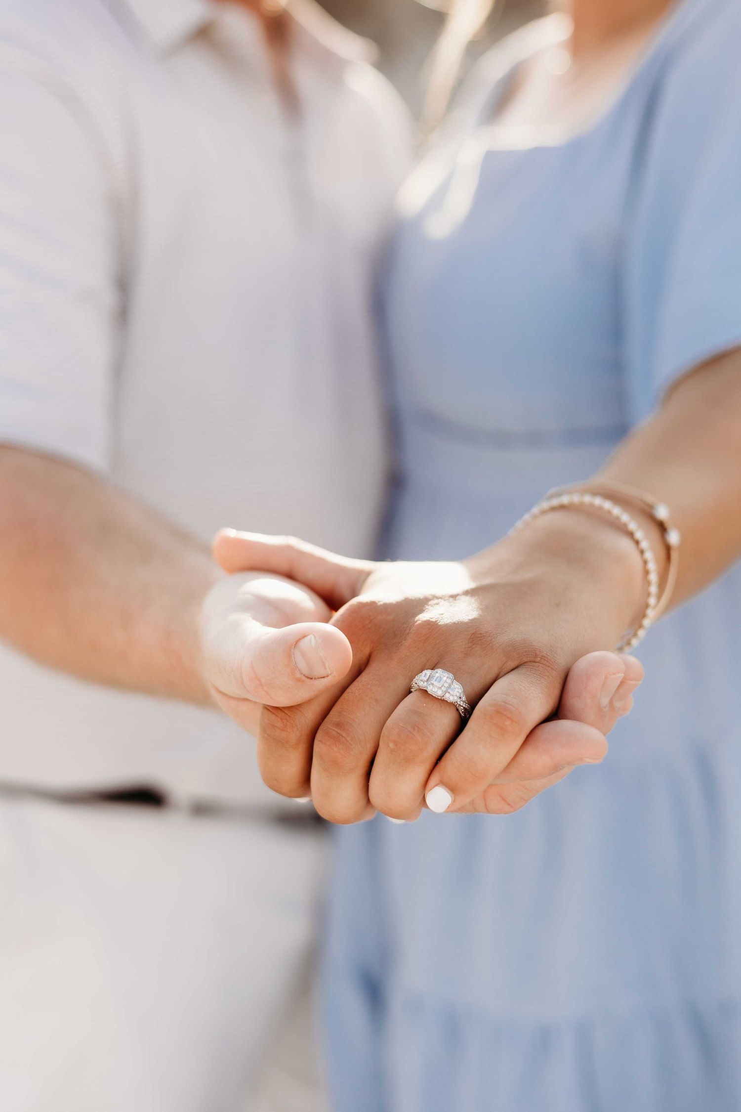 Close-up of hands showing engagement ring during beach proposal.
