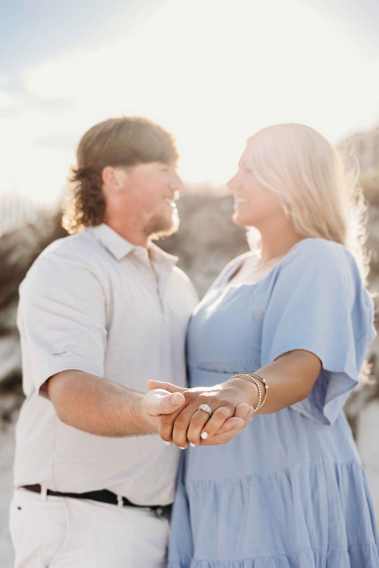 Couple embracing during golden hour engagement shoot on beach.
