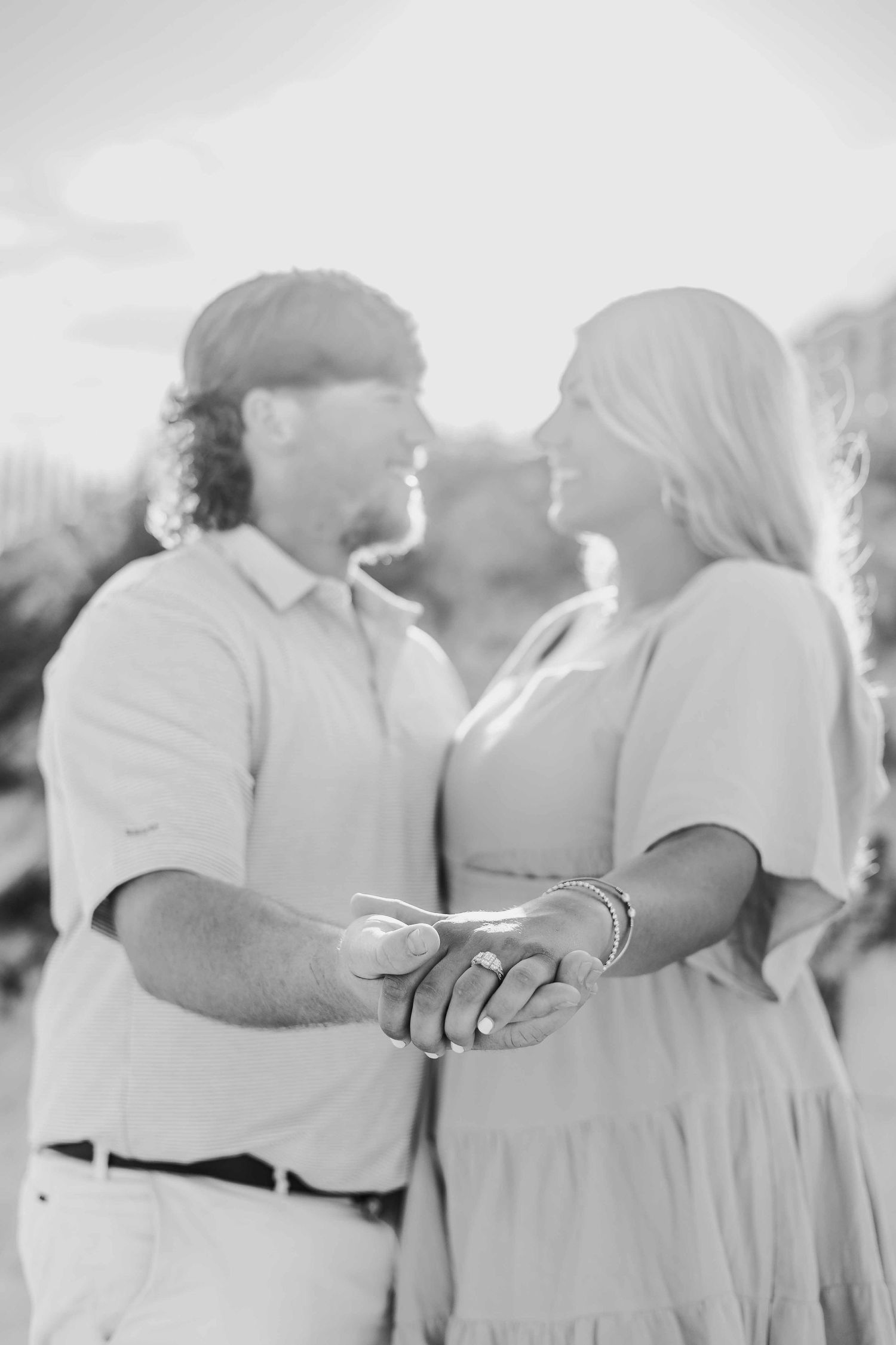 Black and white capture of tender moment during beach engagement session.