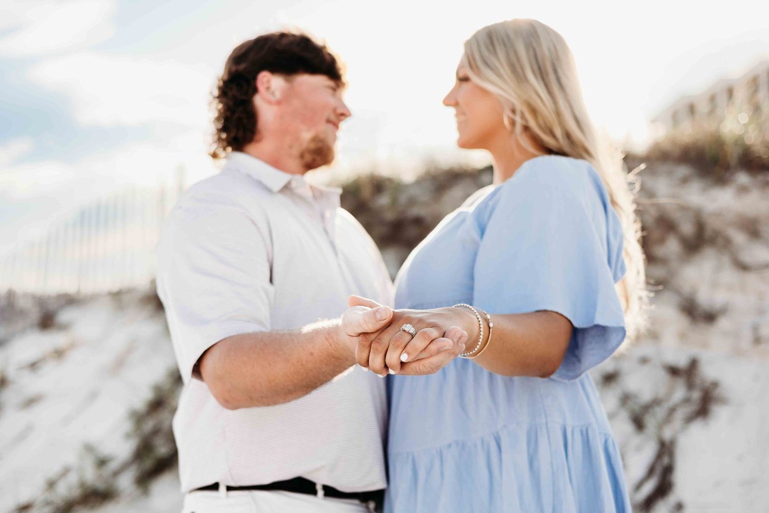 Two people share an intimate moment while standing barefoot in white sand dunes.