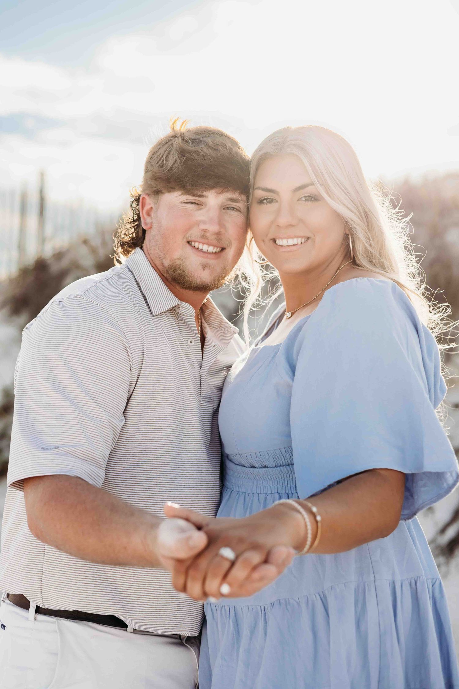 A joyful couple shares laughter during their beach engagement session at sunset.