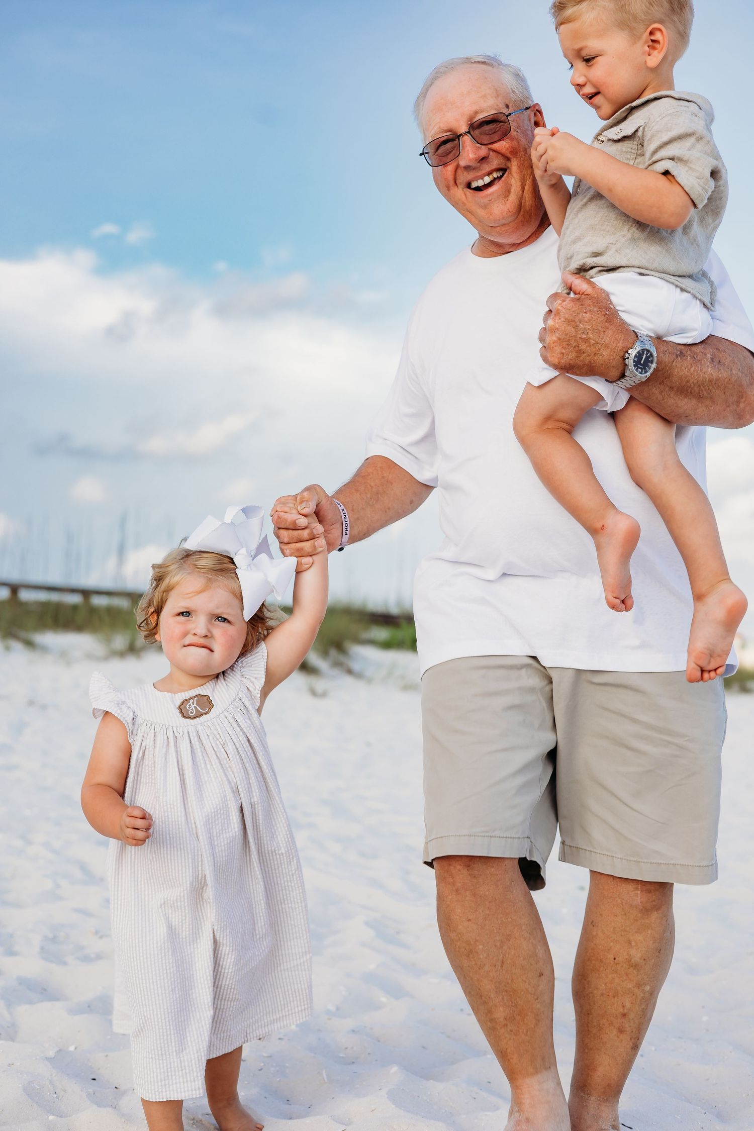 Family members share joyful moments together on a pristine white sandy beach on a sunny day.