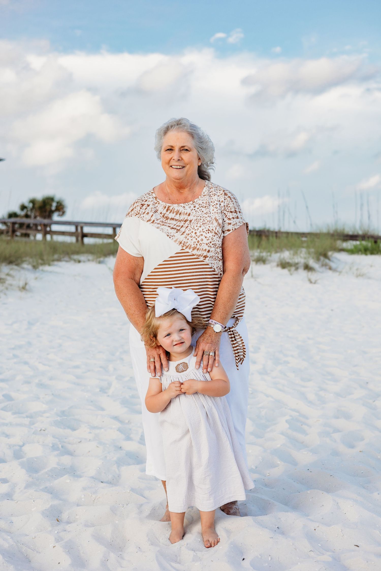Multi-generational family photos captured on a beautiful white sand beach with dunes in the background.