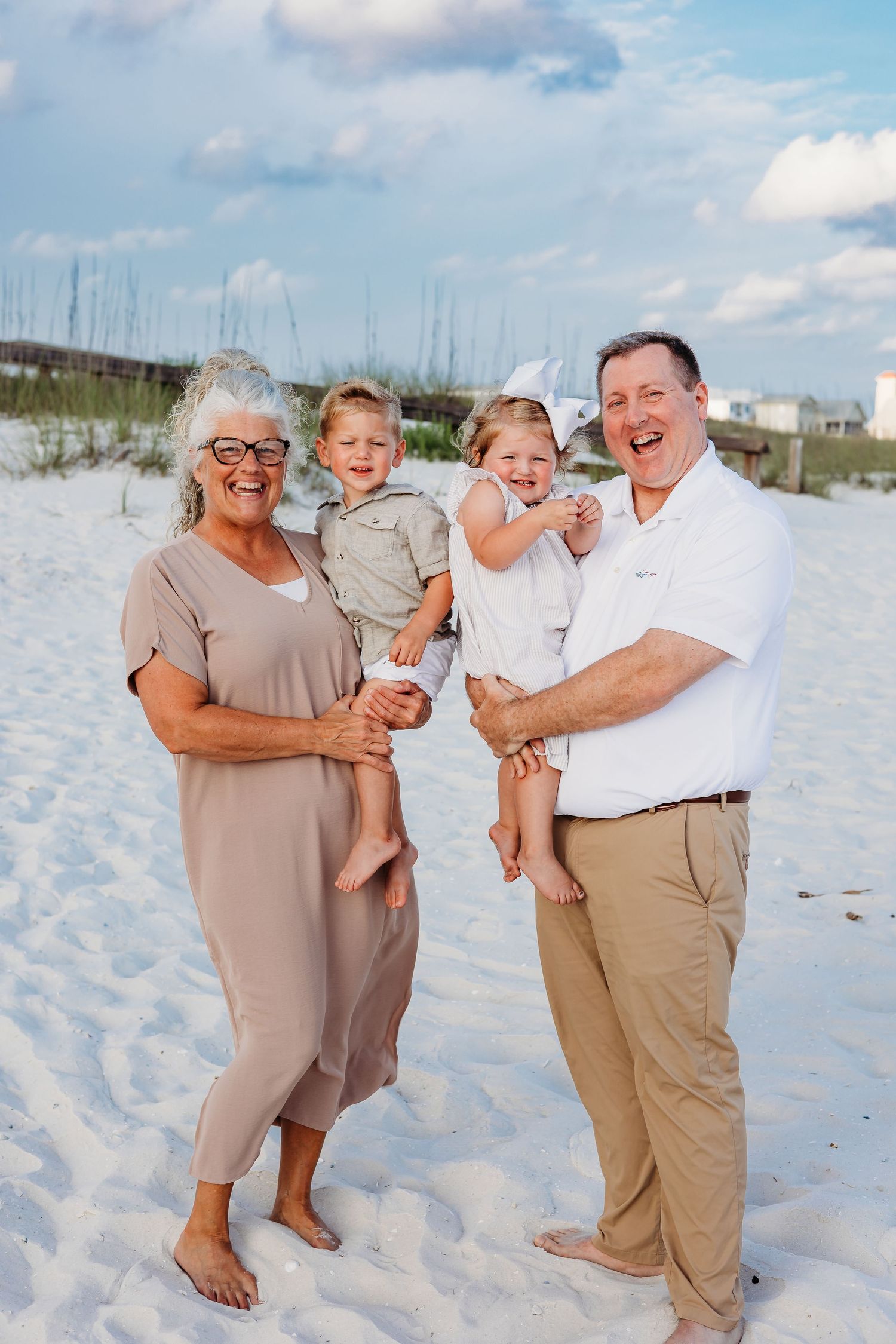 Casual family beach photoshoot showing loving interactions against coastal dunes.