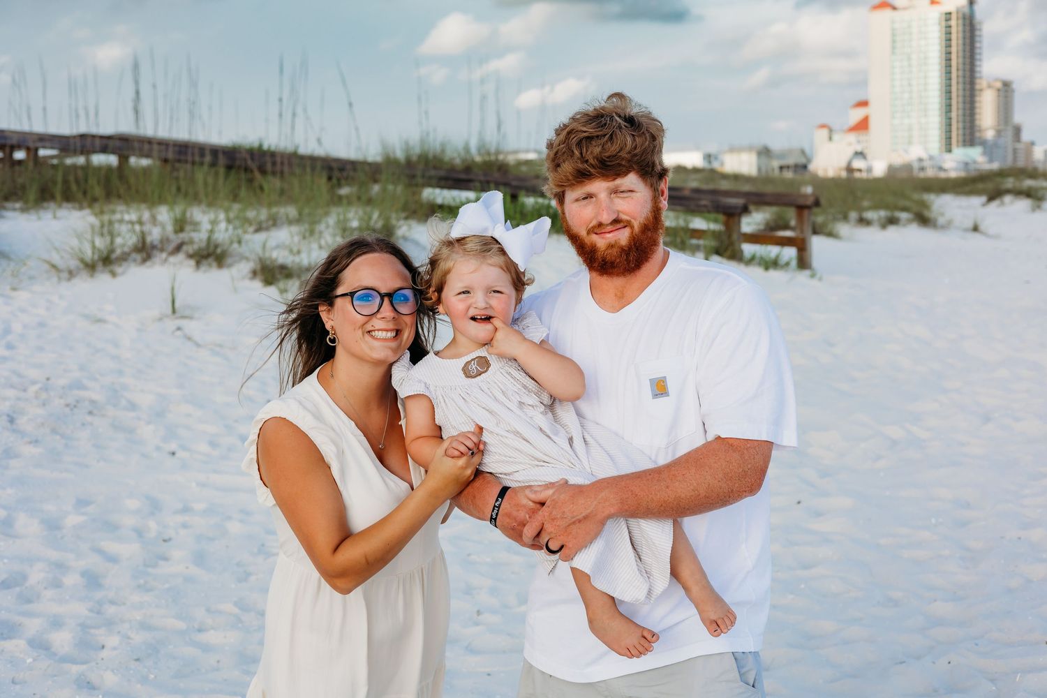 Candid beach photo of a family sharing laughs together while wearing coordinated white outfits.