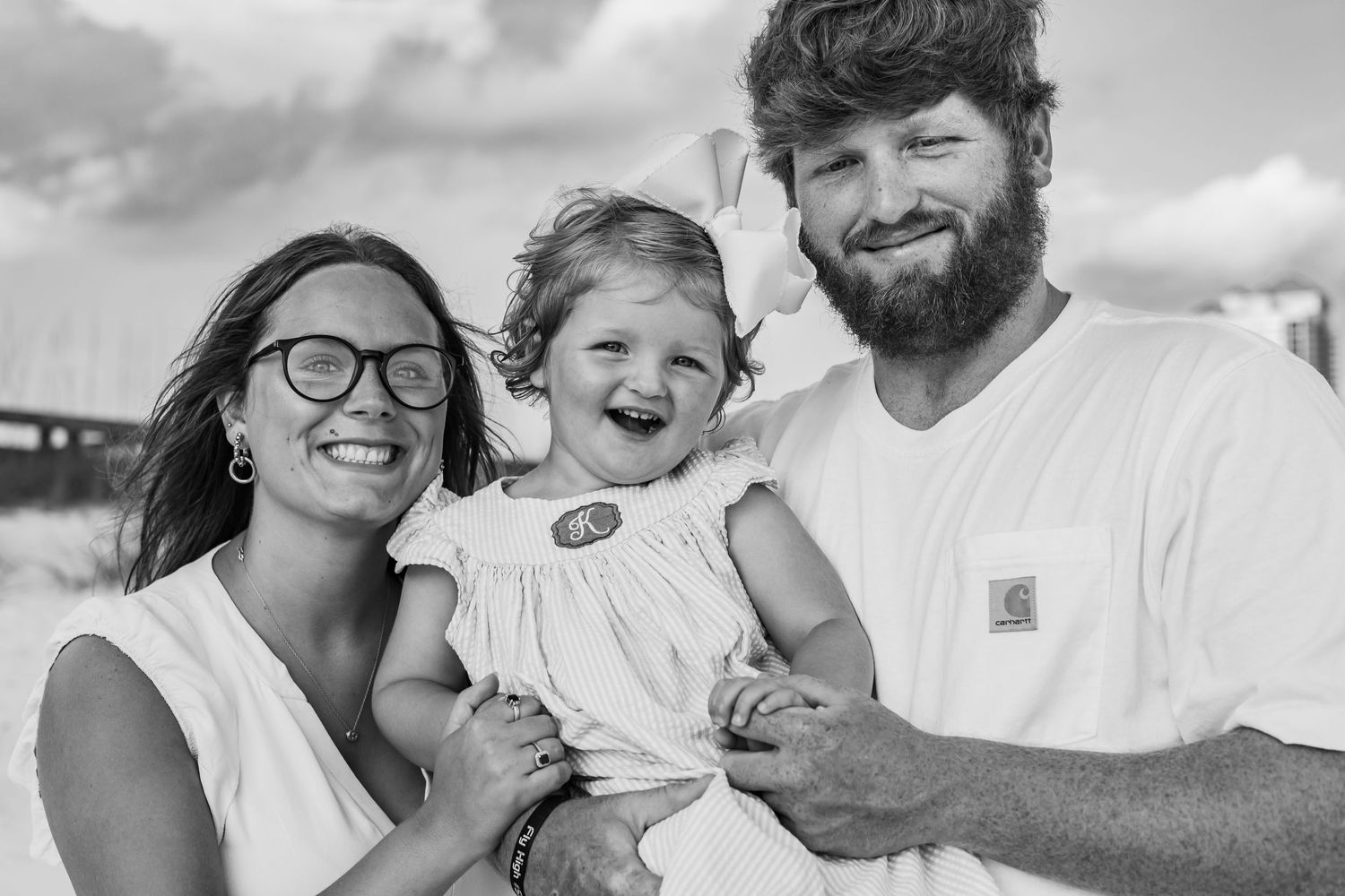 Black and white portrait of a family enjoying a playful moment together on the beach.