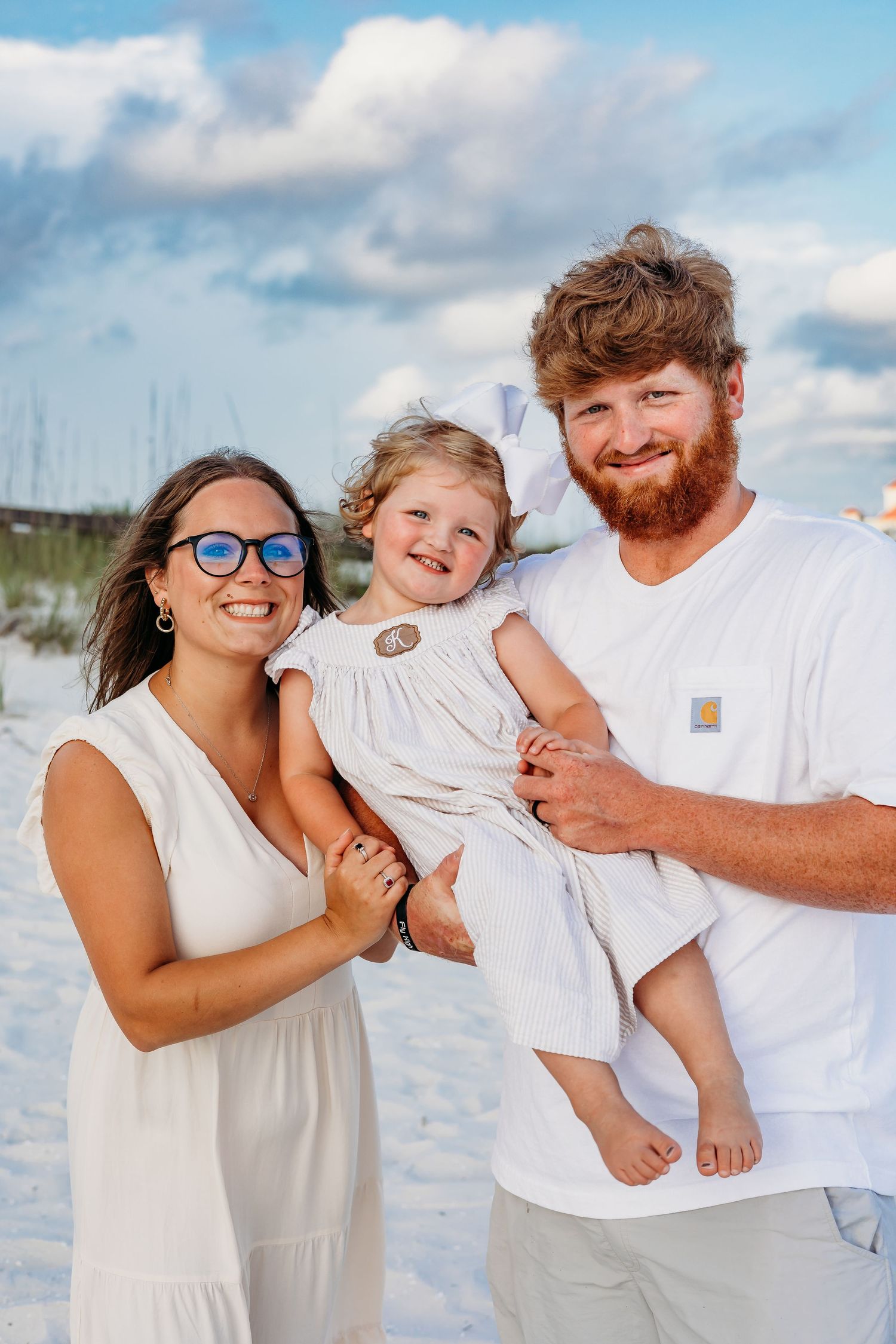 Series of candid beach photos showing a family laughing and embracing in white outfits.