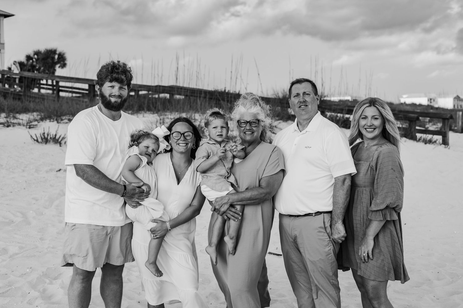 Black and white portrait of a family group gathered together on a beach.