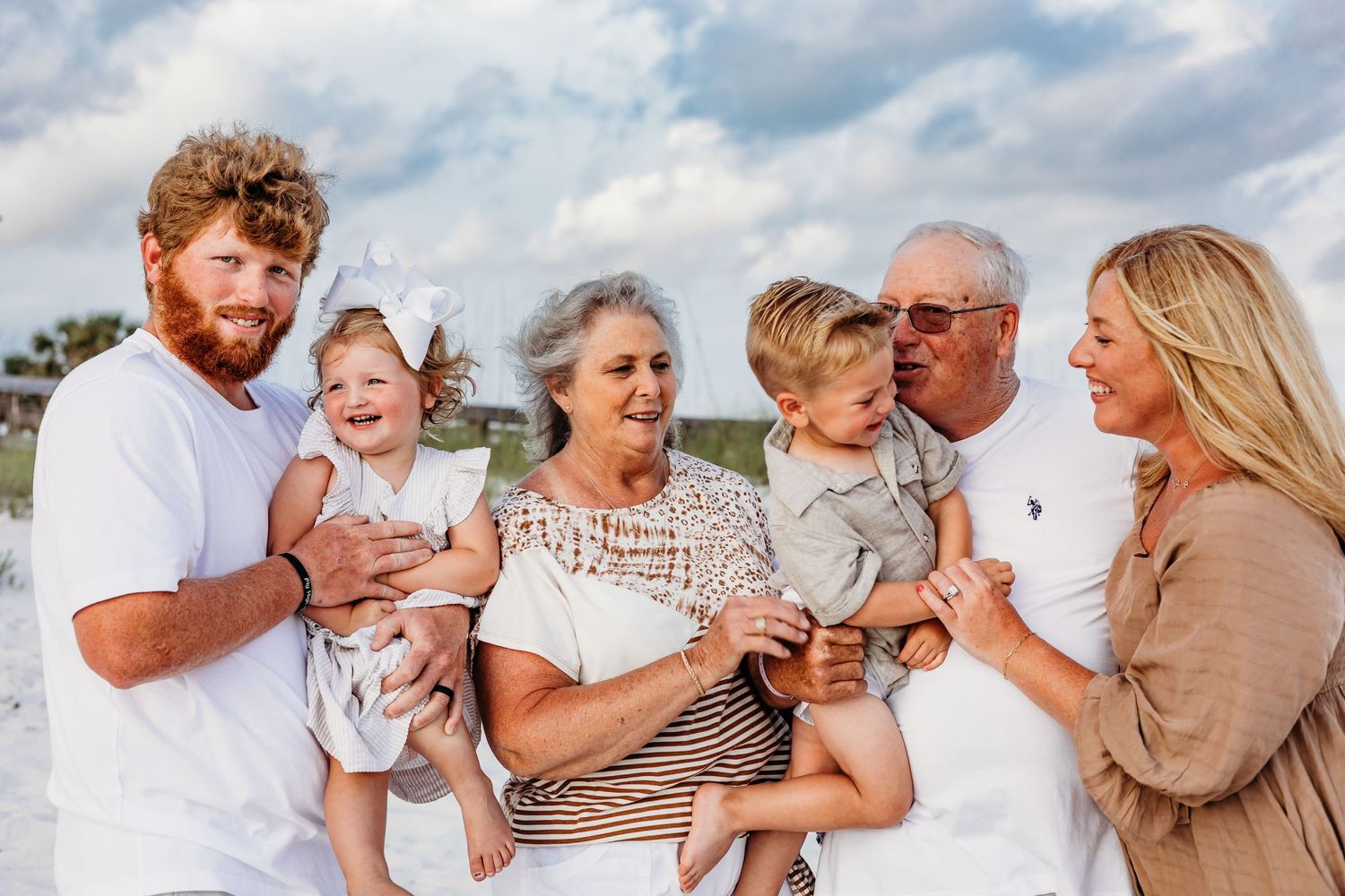 Three generations share joyful moments playing together on a sunny beach.