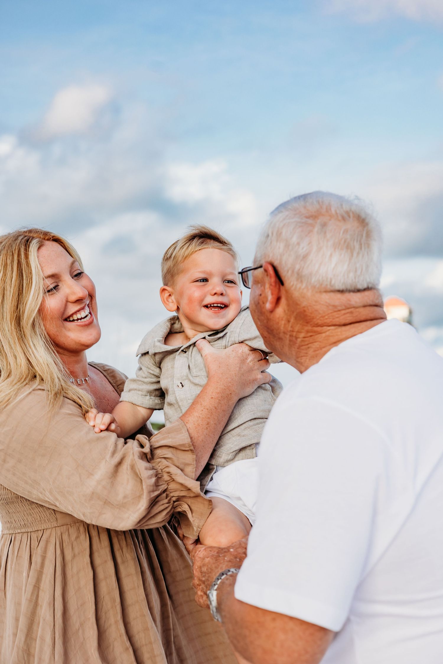 Family members share loving embraces and laughter against a bright blue sky background.