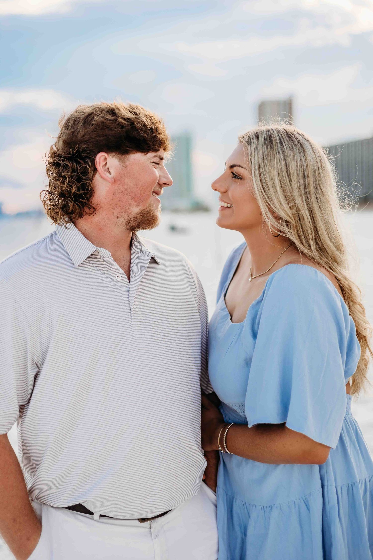 Intimate beach photoshoot featuring couple in white and powder blue casual wear.