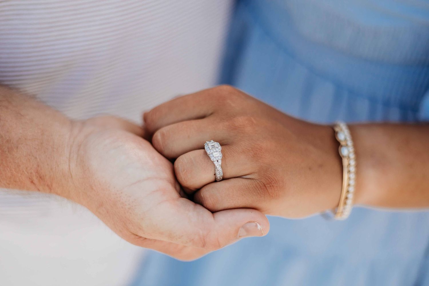 Close-up detail shots of hands and rings during a beach engagement photoshoot.