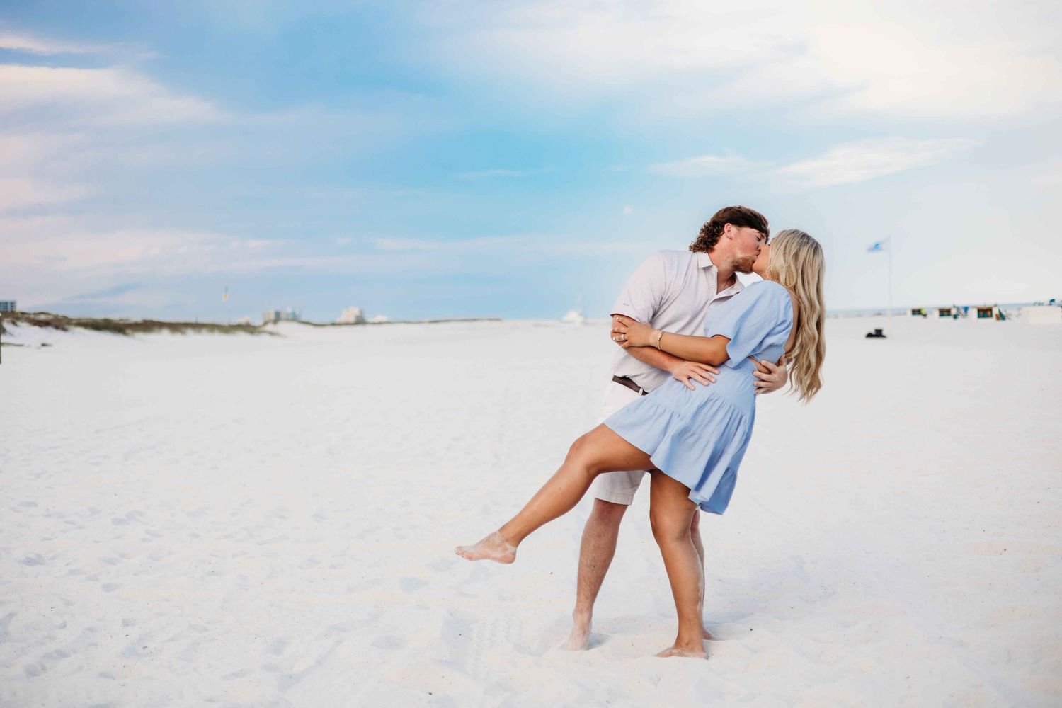 Couple enjoying playful moments together on sandy beach during photo session.