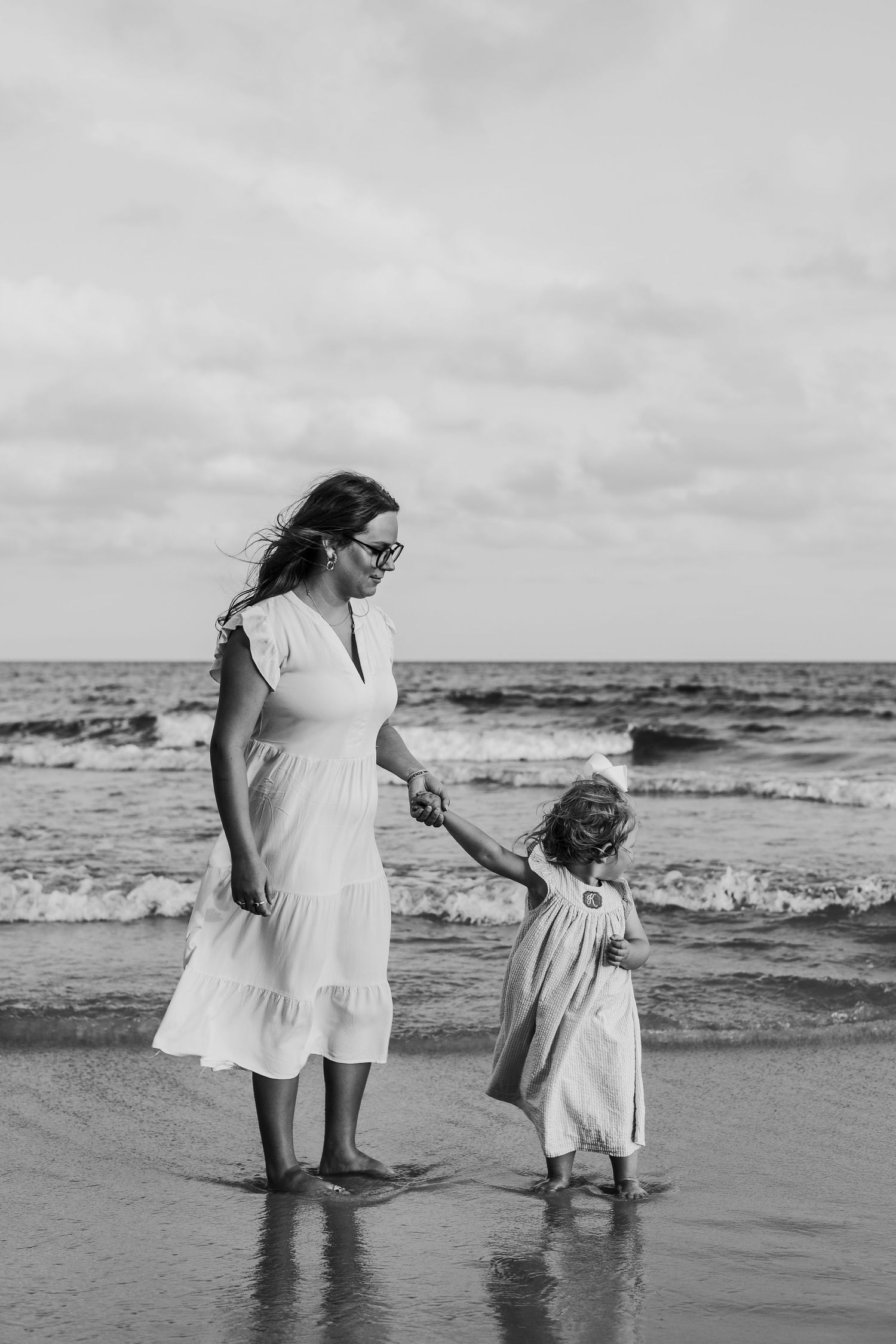Black and white photo of people enjoying a beach day together near the ocean waves.