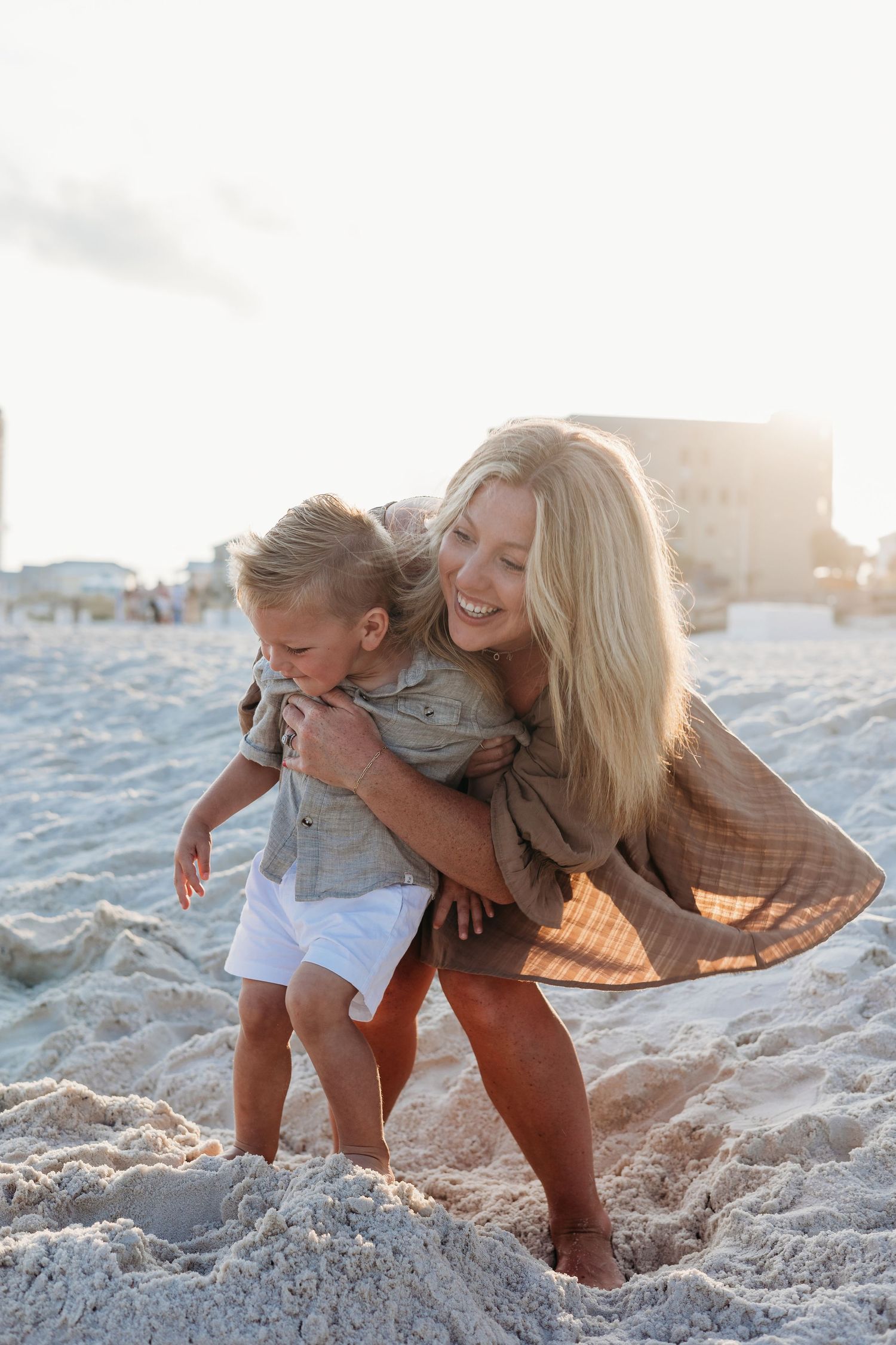 Candid beach scene showing affectionate interaction and laughter while playing in the sand.