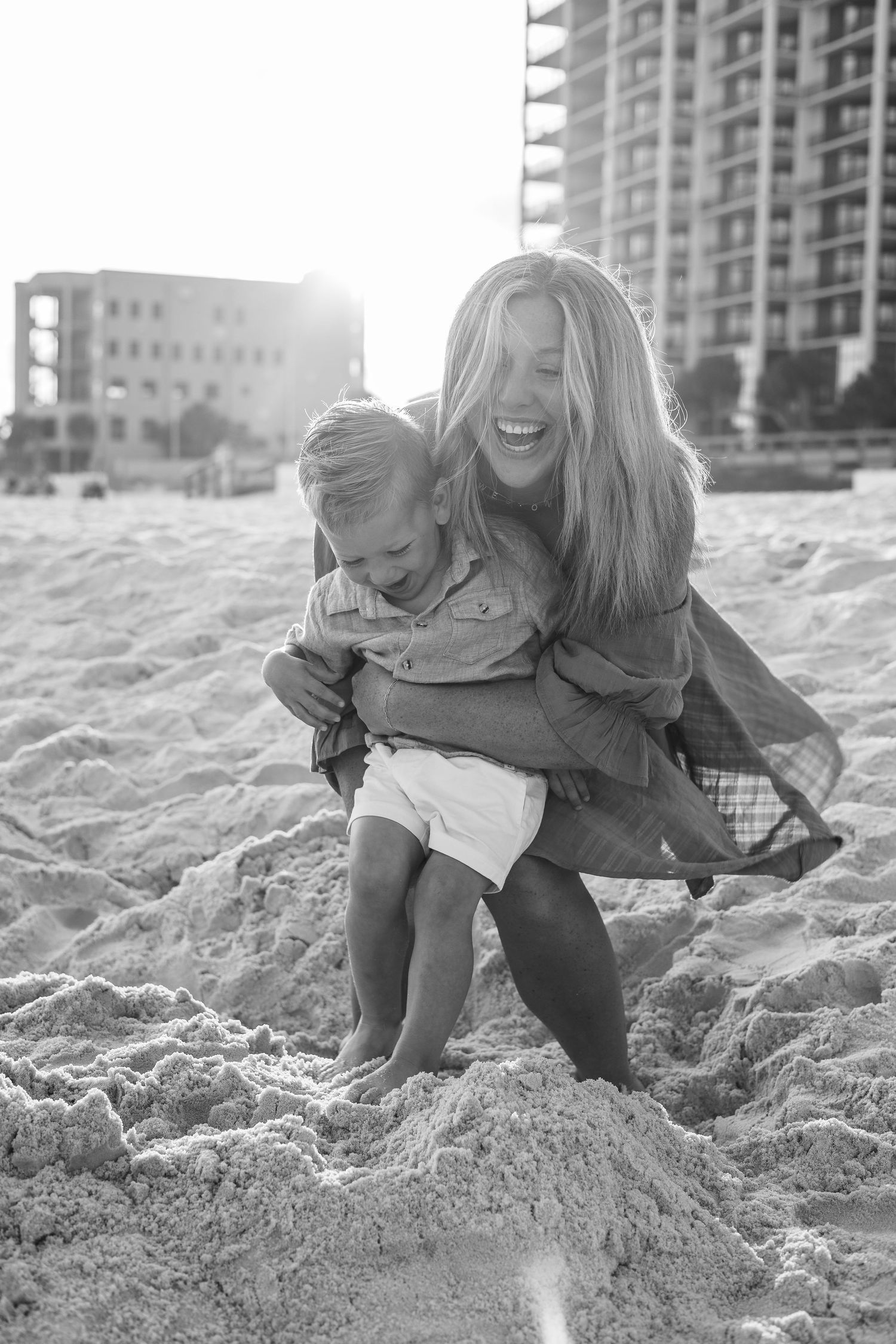 Black and white photo of beachside fun with apartment buildings visible in the background.