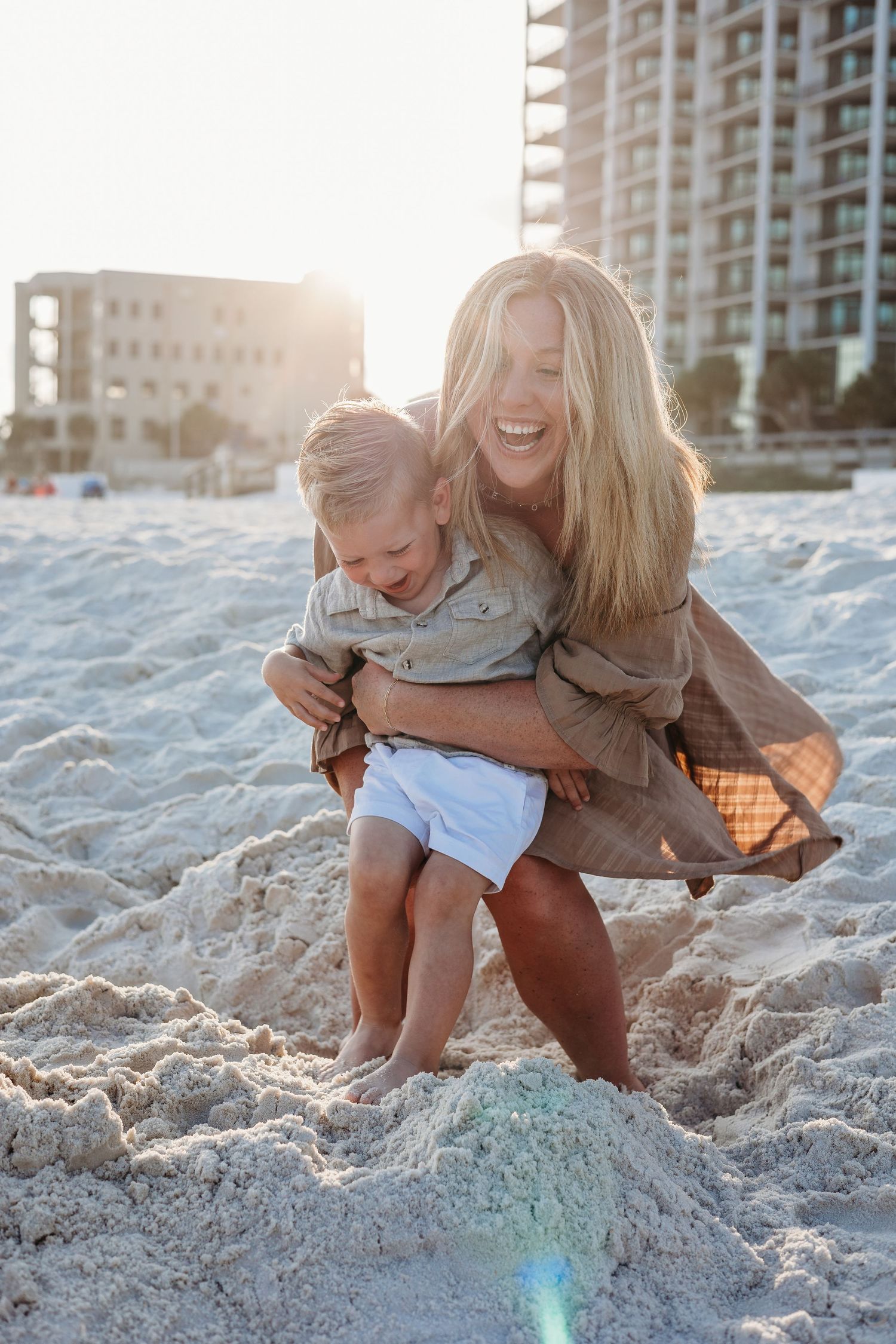 Sunset beach scene with warm embraces and laughter against coastal buildings.