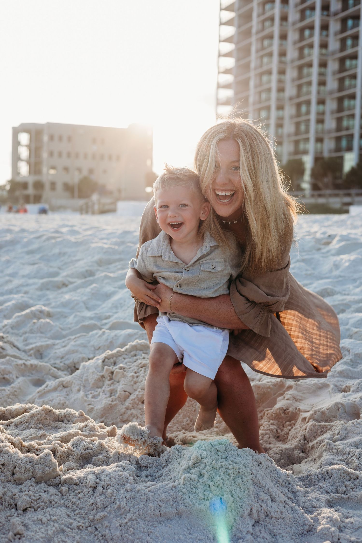 Genuine laughter and joy captured during a playful beach photoshoot at golden hour.