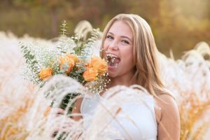 Joyful portrait with orange flowers and dried pampas grass in golden sunlight.