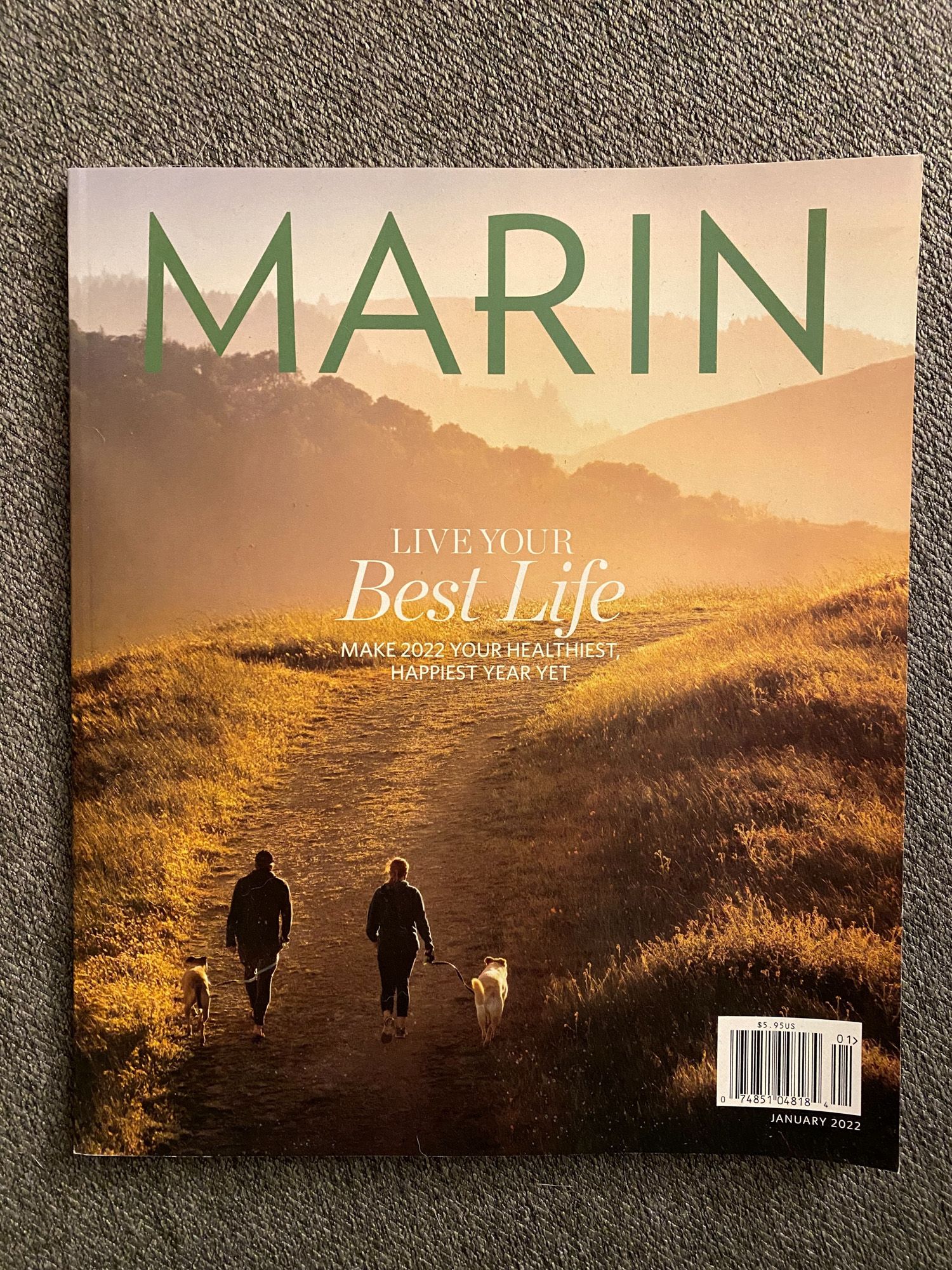 Magazine cover of Marin showing silhouettes of two people and a dog walking on a hilltop trail at sunset.