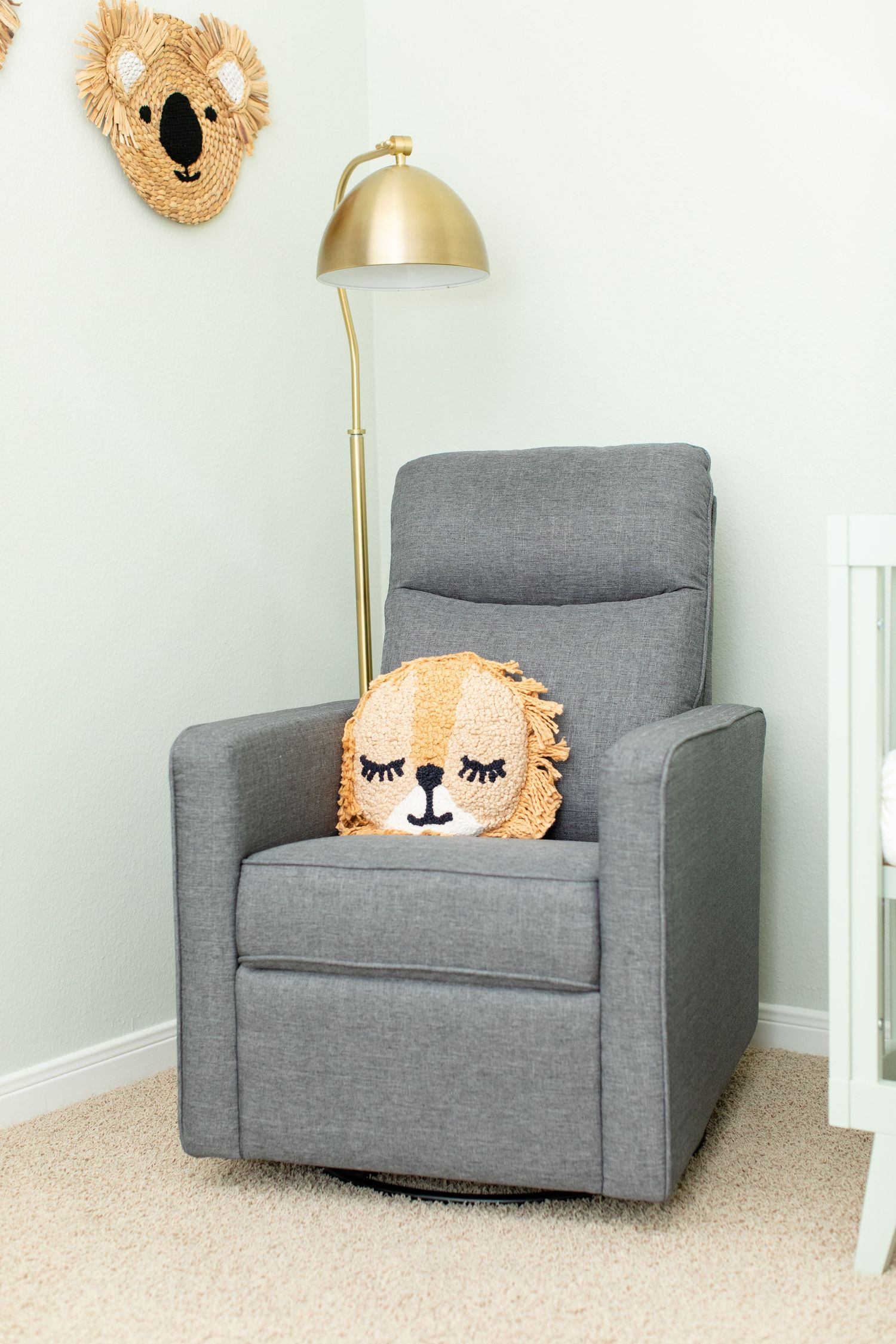 Gray nursery glider with gold floor lamp and koala wall decor.