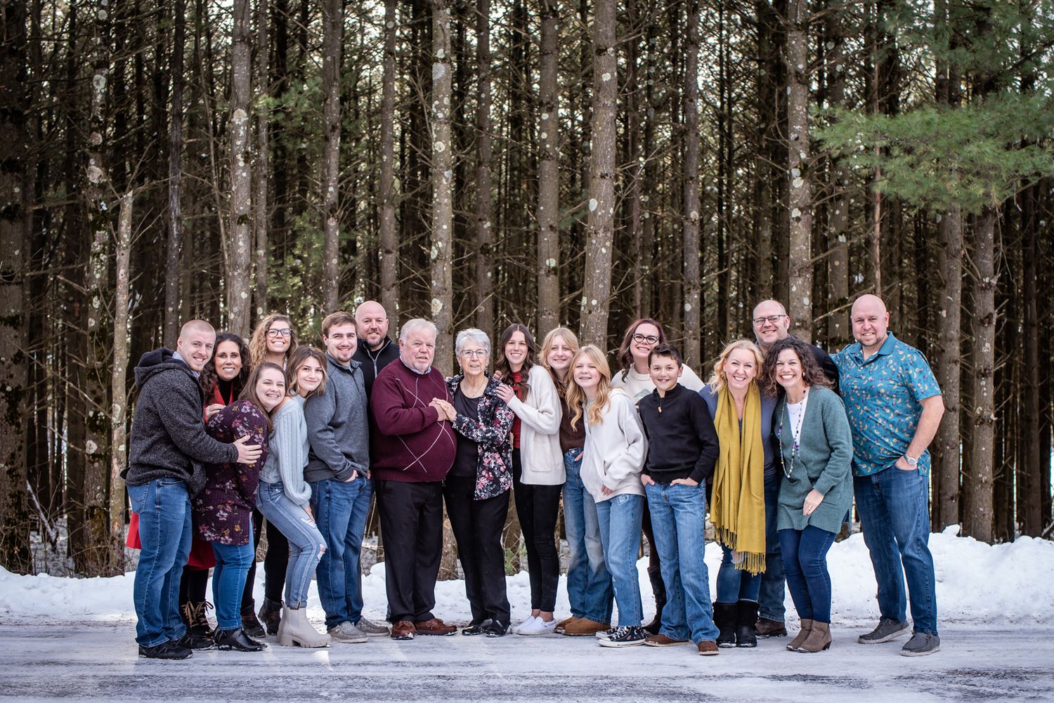 Extended family portrait in front of a snowy evergreen forest backdrop.