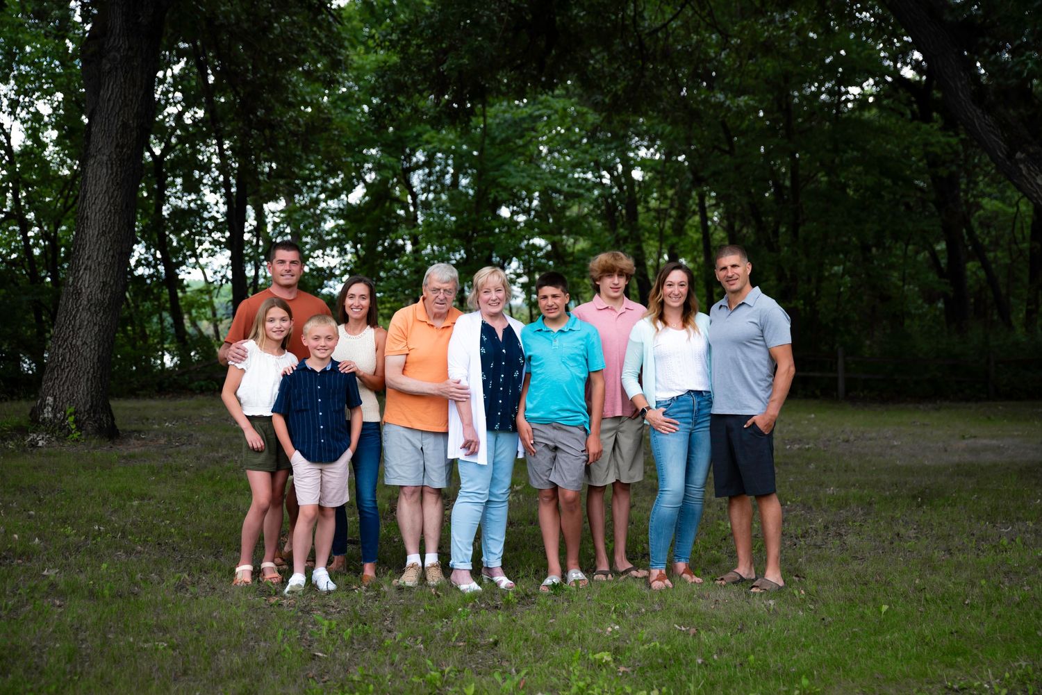 Group photo of people standing together in a lush green park setting during summer.