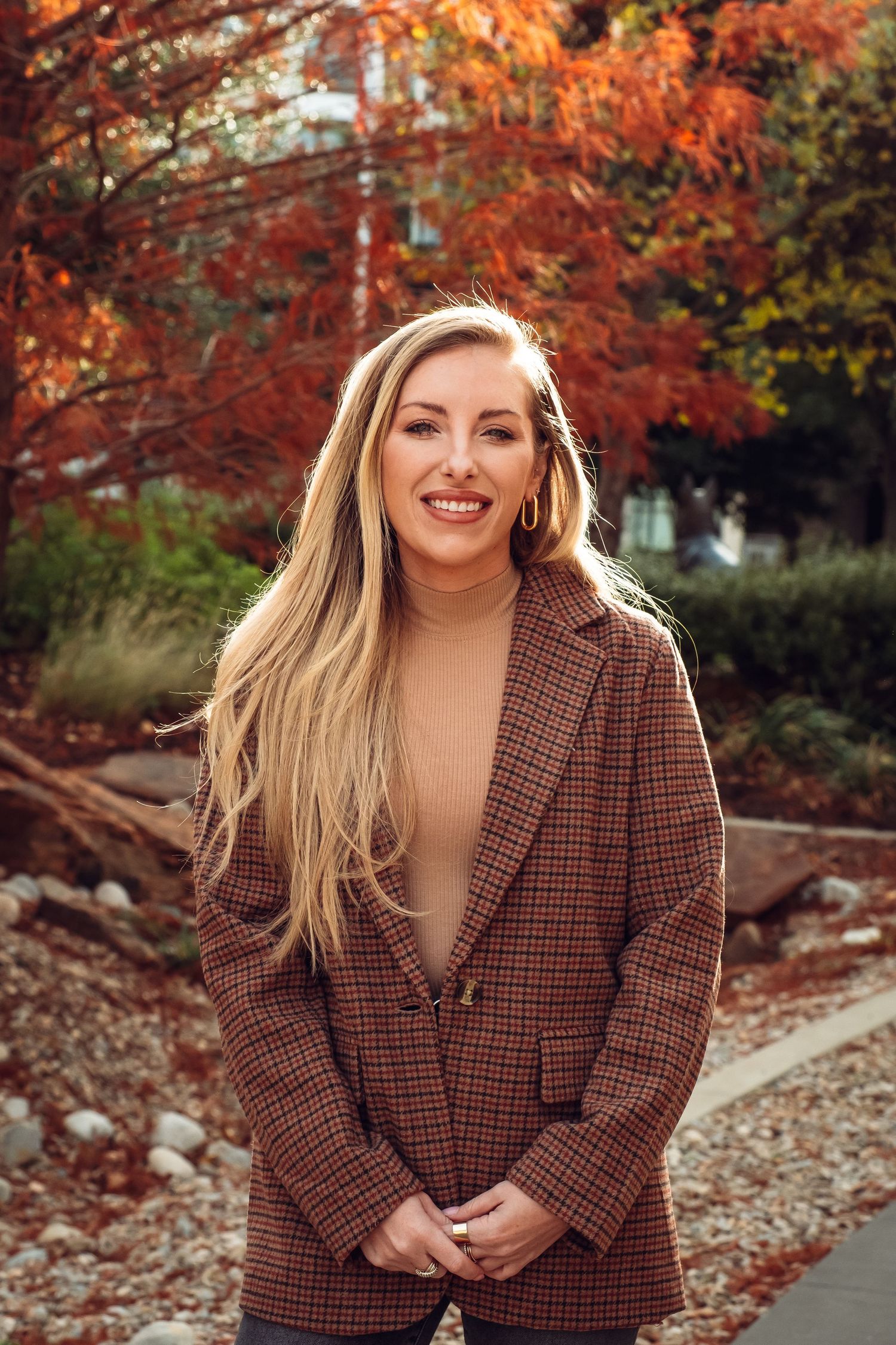 Professional outdoor portrait session with autumn colors and falling leaves in background.
