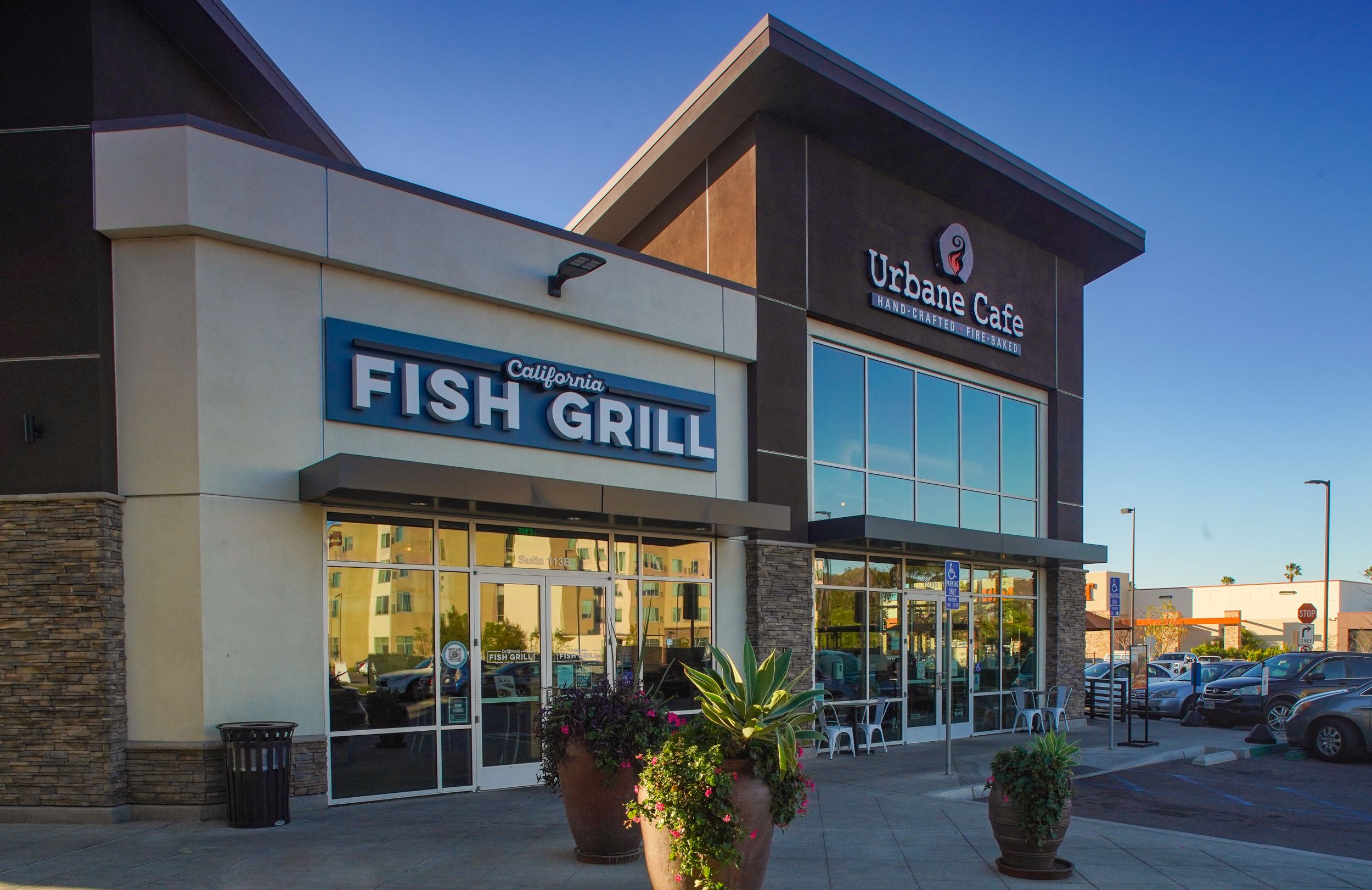 Exterior storefronts of California Fish Grill and Urbane Cafe restaurants in a modern retail plaza.