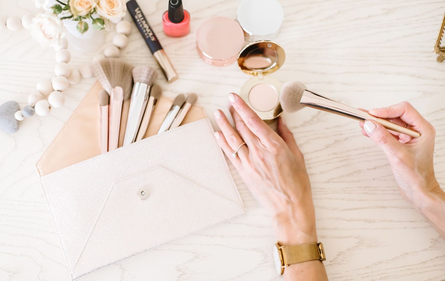 Flatlay of beauty products and accessories on white surface.