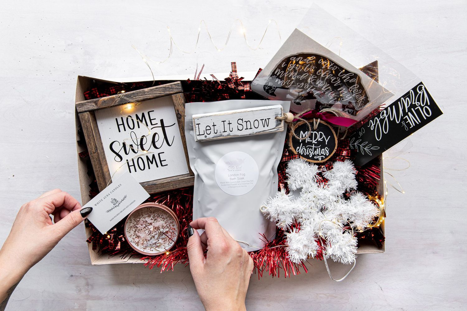 Holiday themed flatlay with home decor signs and festive decorations on white surface.