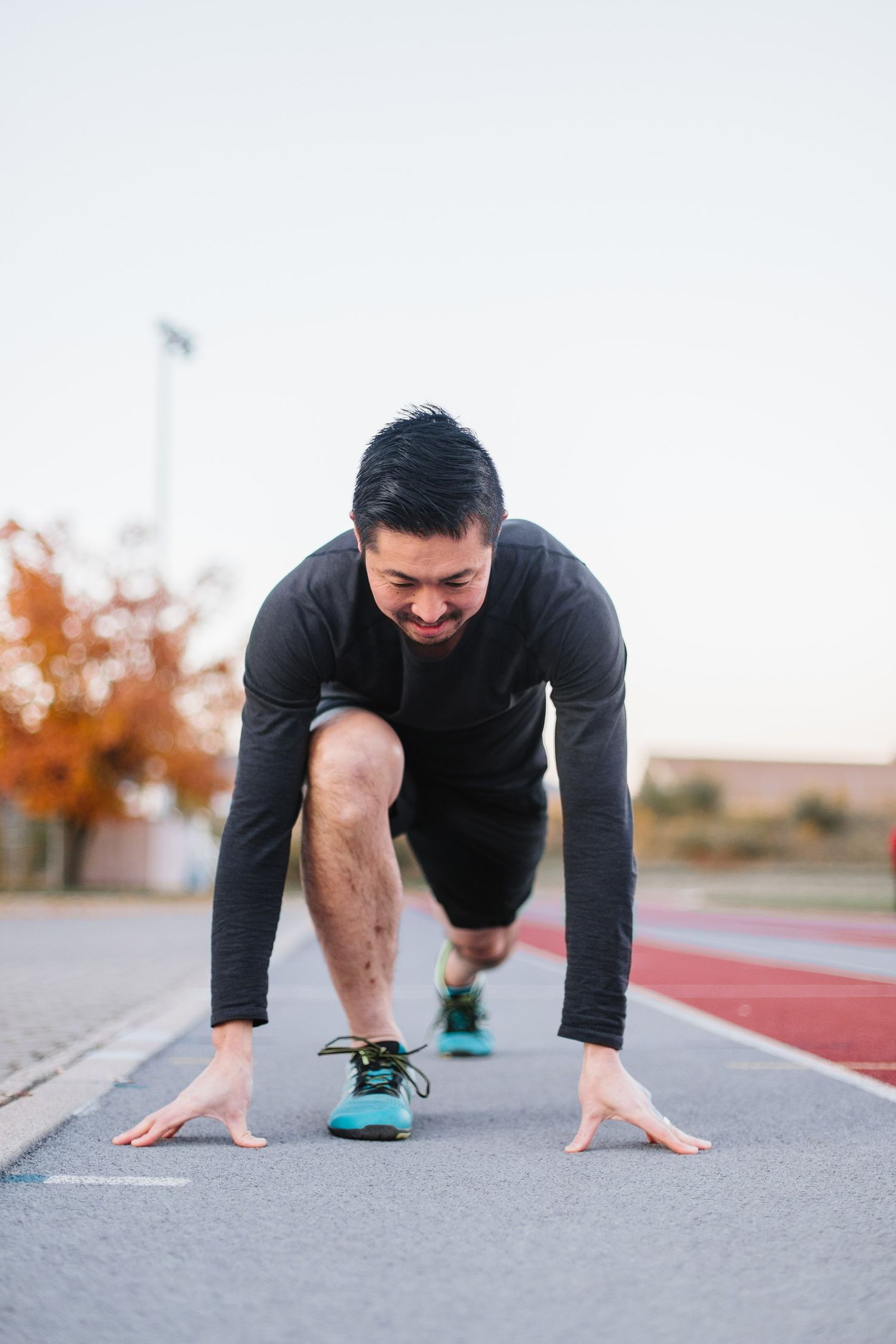 Person in black athletic wear doing push-up position on outdoor track.