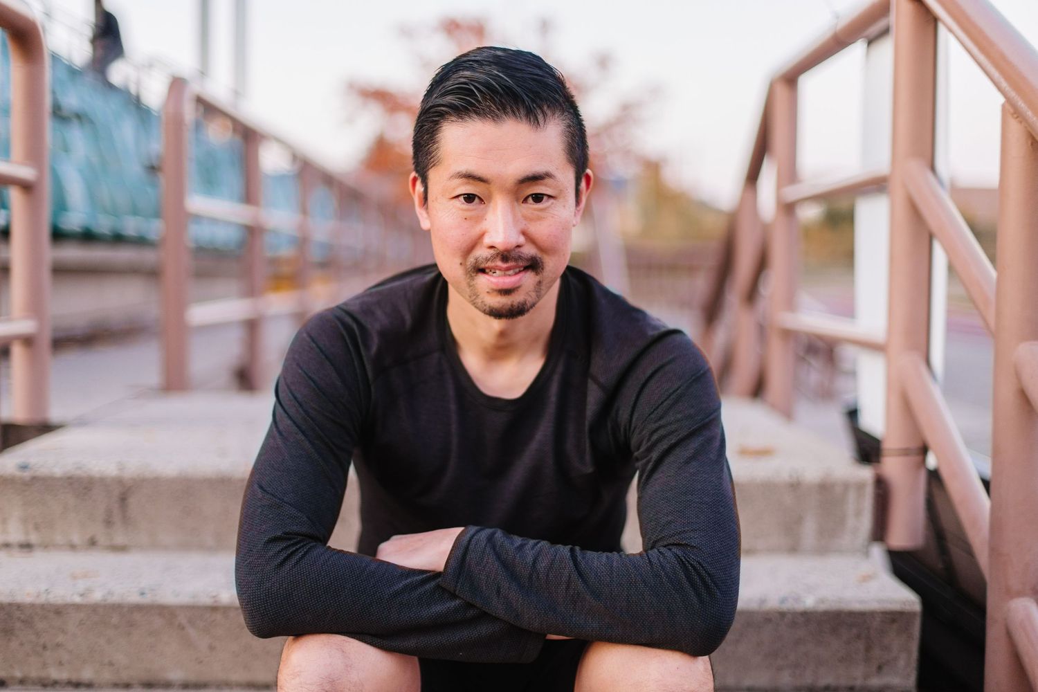 Person in black clothing sitting on outdoor steps with casual pose.