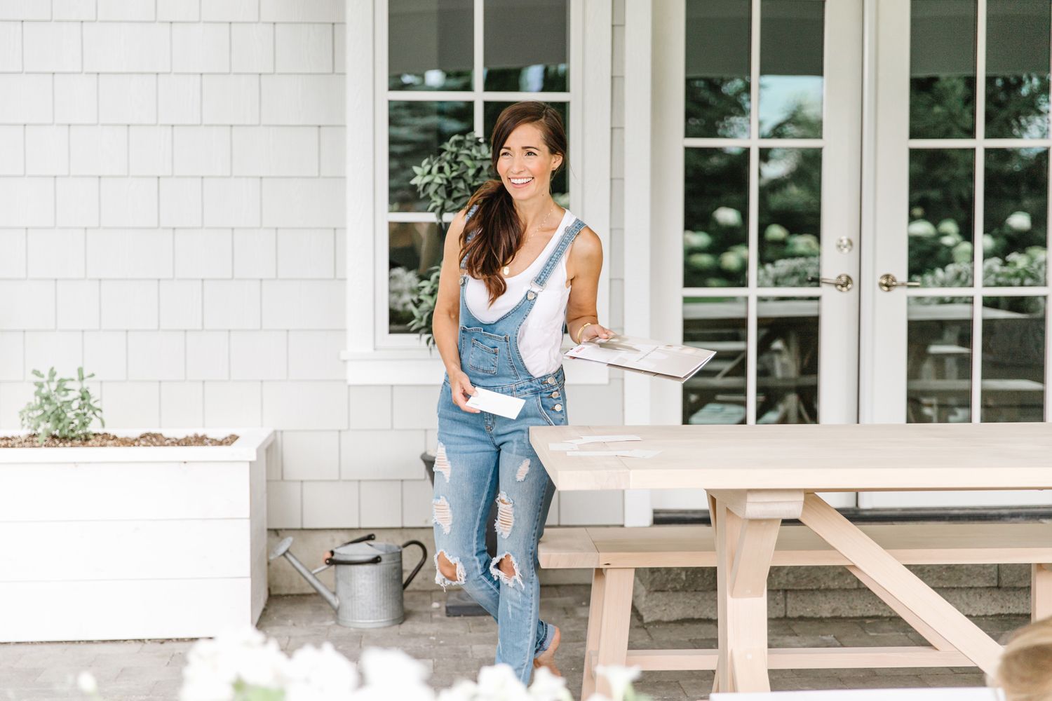 Casual outdoor lifestyle shot on white farmhouse porch with denim overalls.