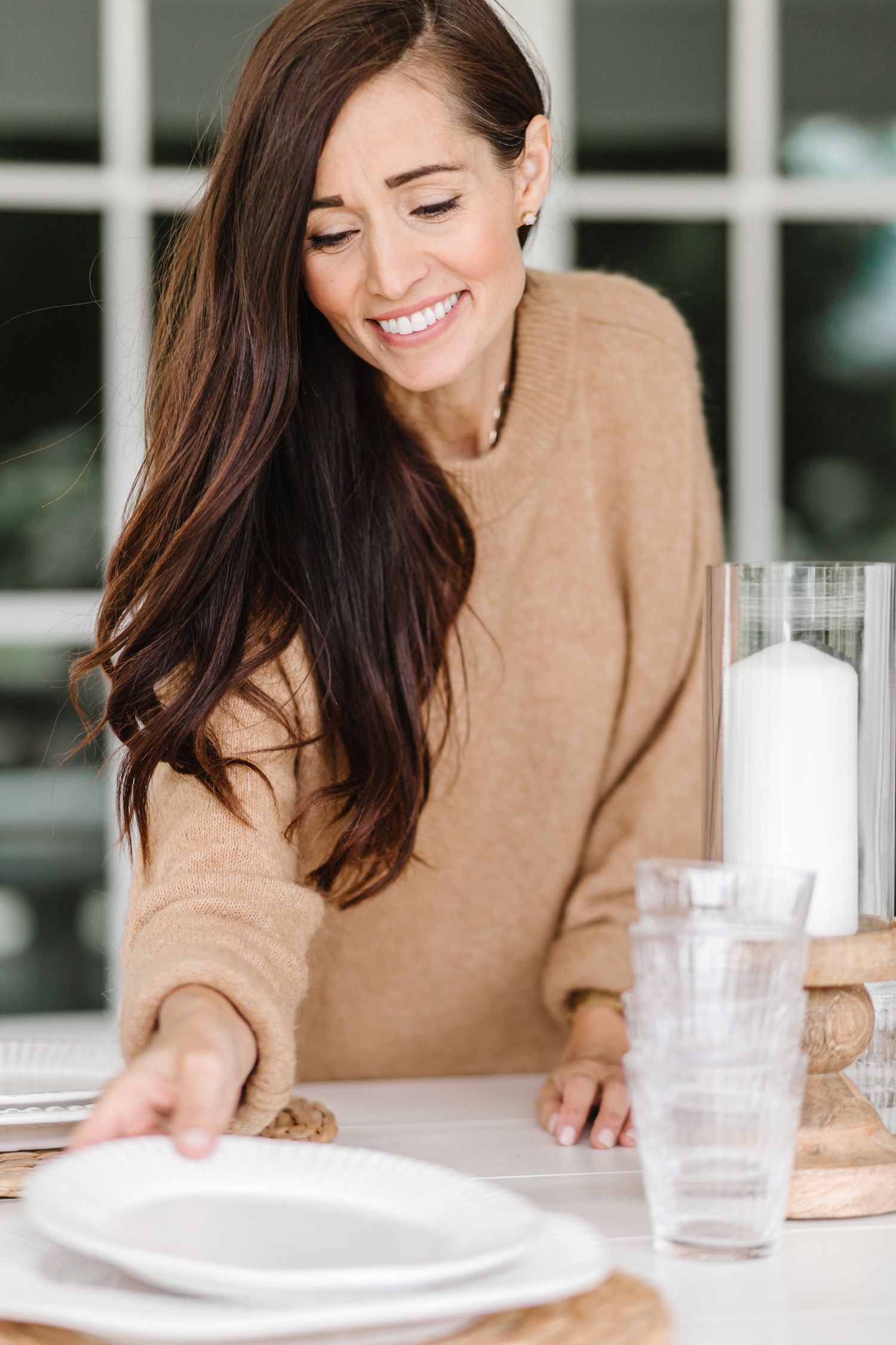 Warm interior scene with tan sweater and table settings in natural light.