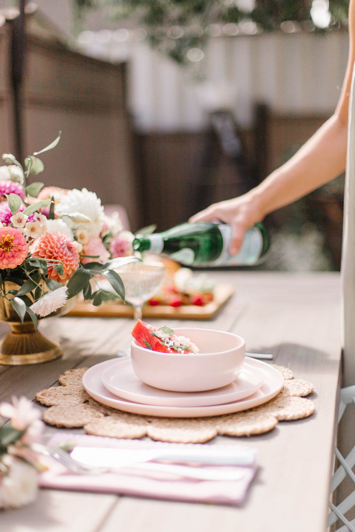 Table setting with pink plates, floral arrangements and decorative placemats.