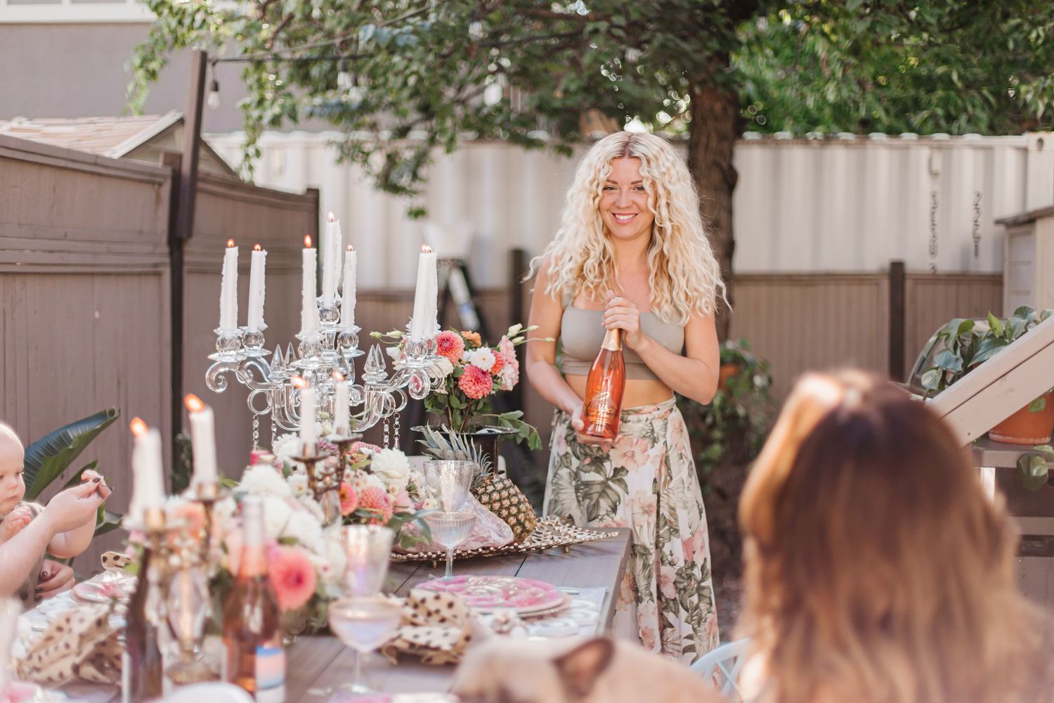 Elegant outdoor party table setting with pink floral arrangements and delicate place settings.