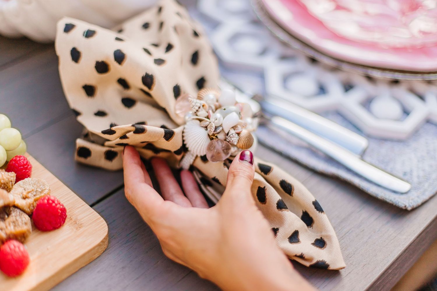 Close-up of polka dot napkins and fresh berries on wooden serving board at table setting.