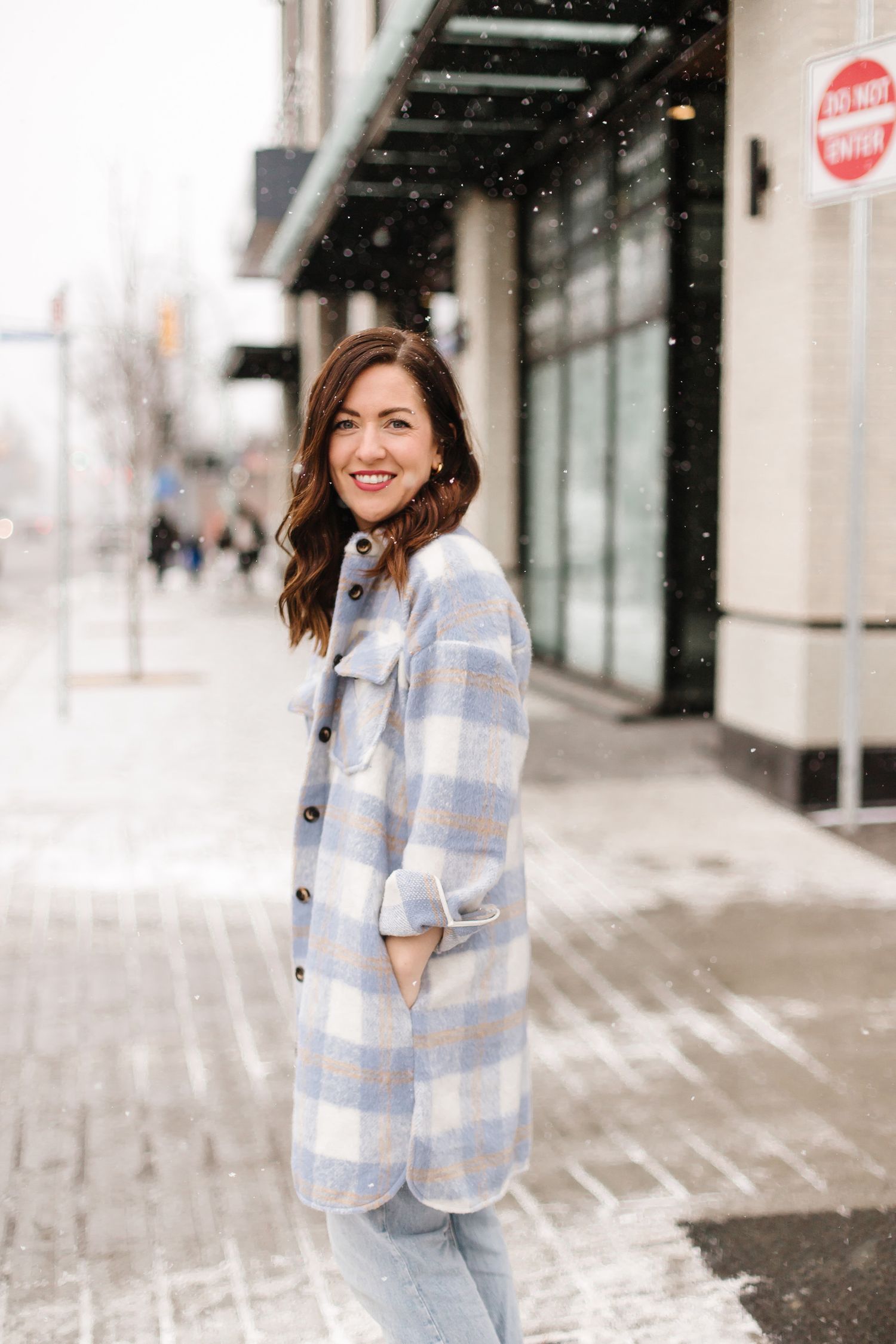 Snowy urban street scene with storefronts and winter atmosphere.