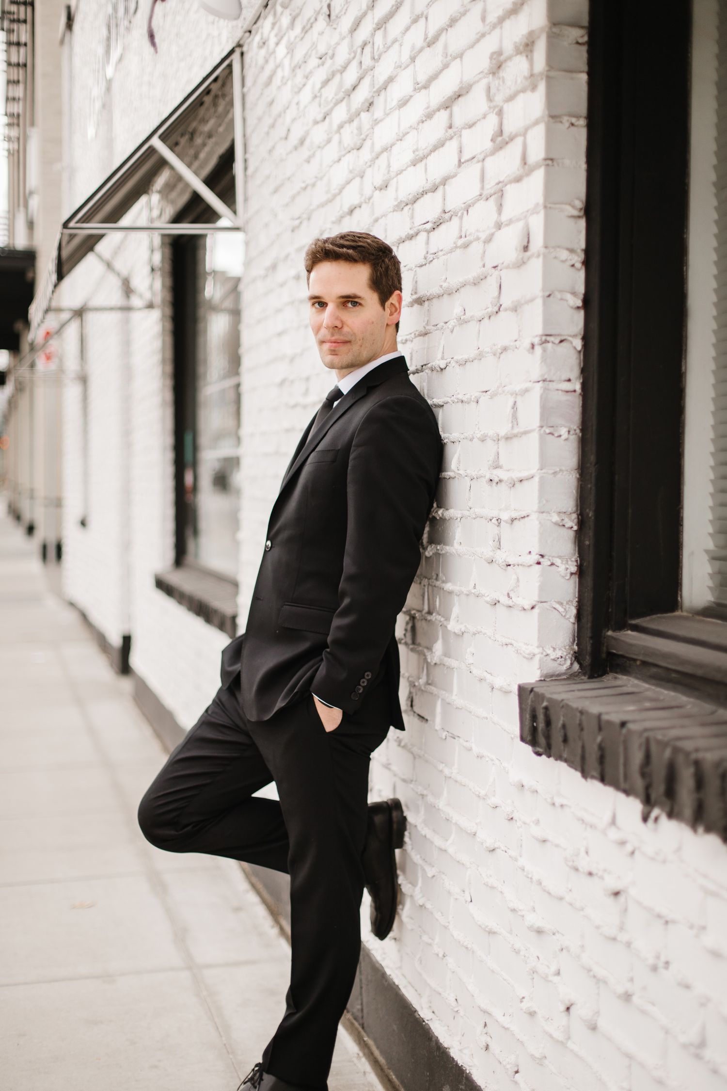 Professional business portraits against white brick wall showing different poses in formal attire.