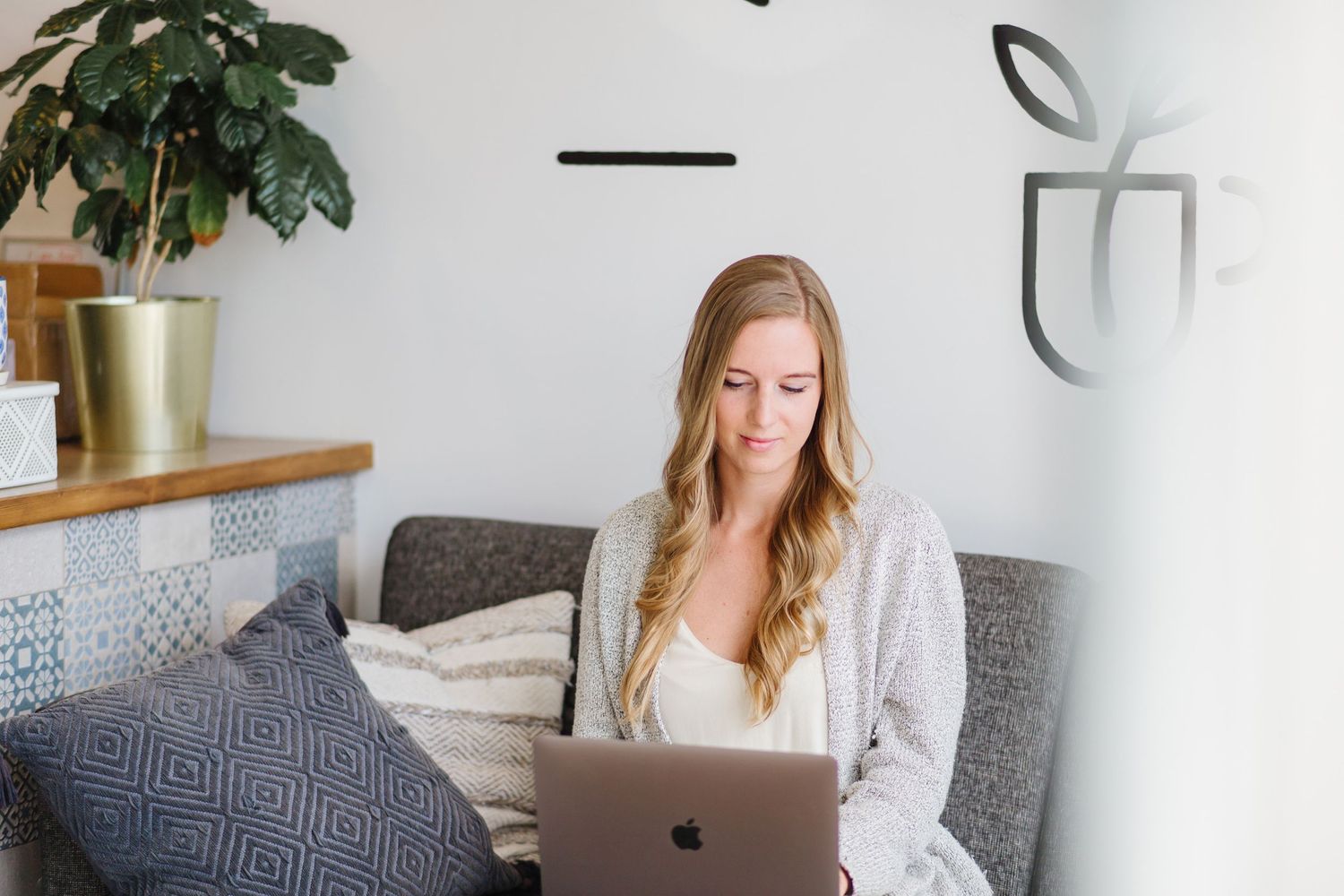 Modern home office setup with laptop, plants and minimalist white decor.