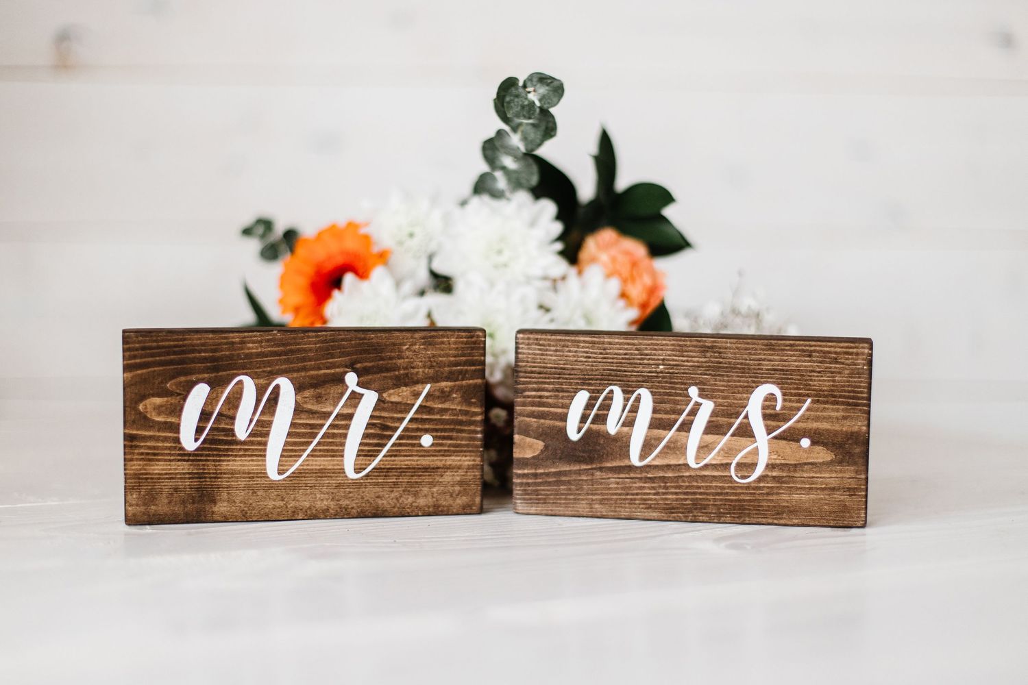Wooden Mr. and Mrs. wedding signs decorated with orange and white flowers.