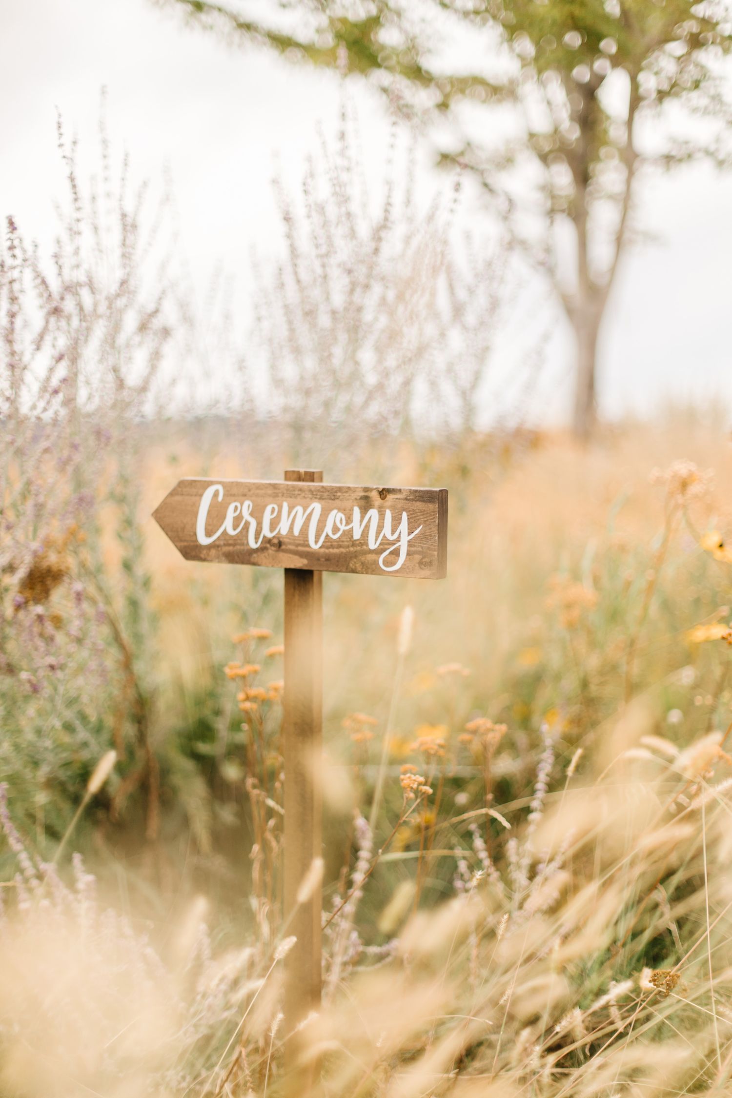 Rustic wooden ceremony sign in a dreamy wildflower field.