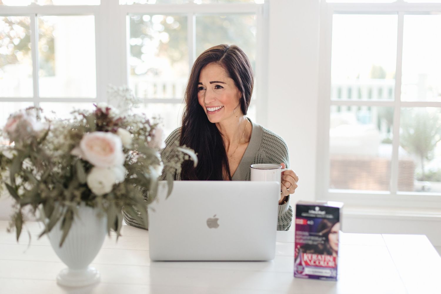 Bright workspace with MacBook, flowers and modern office accessories.