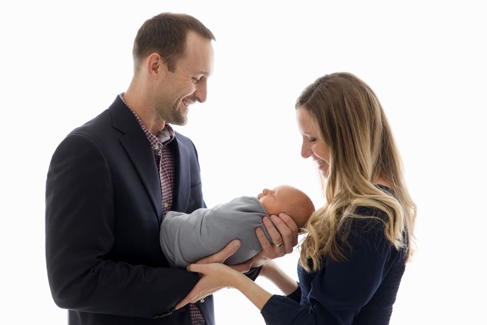 Tender family moment captured against white backdrop in formal wear.