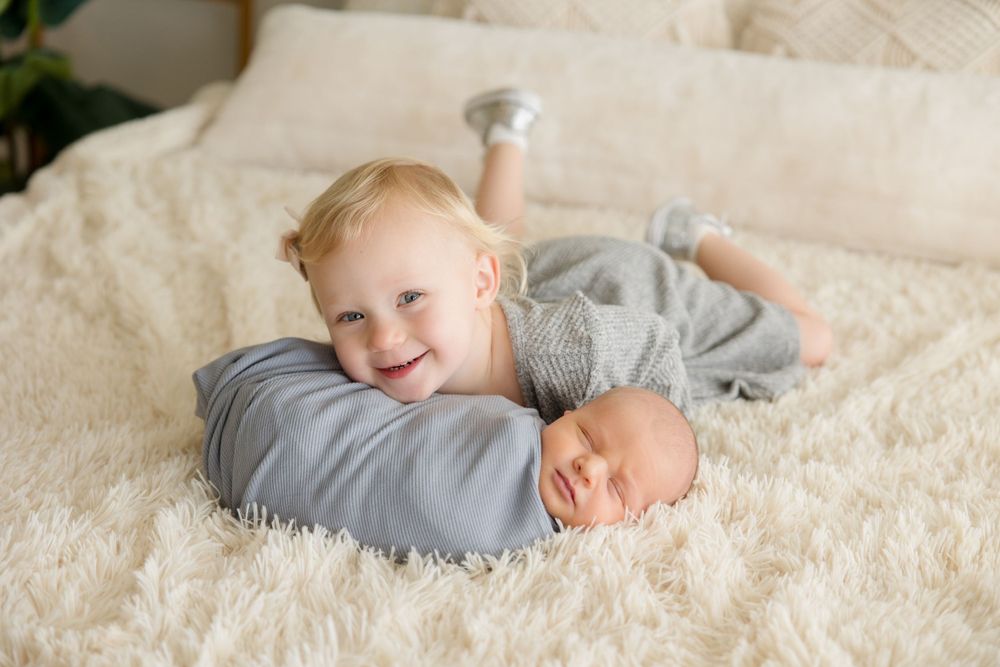 Joyful moment between siblings on white textured bedding.